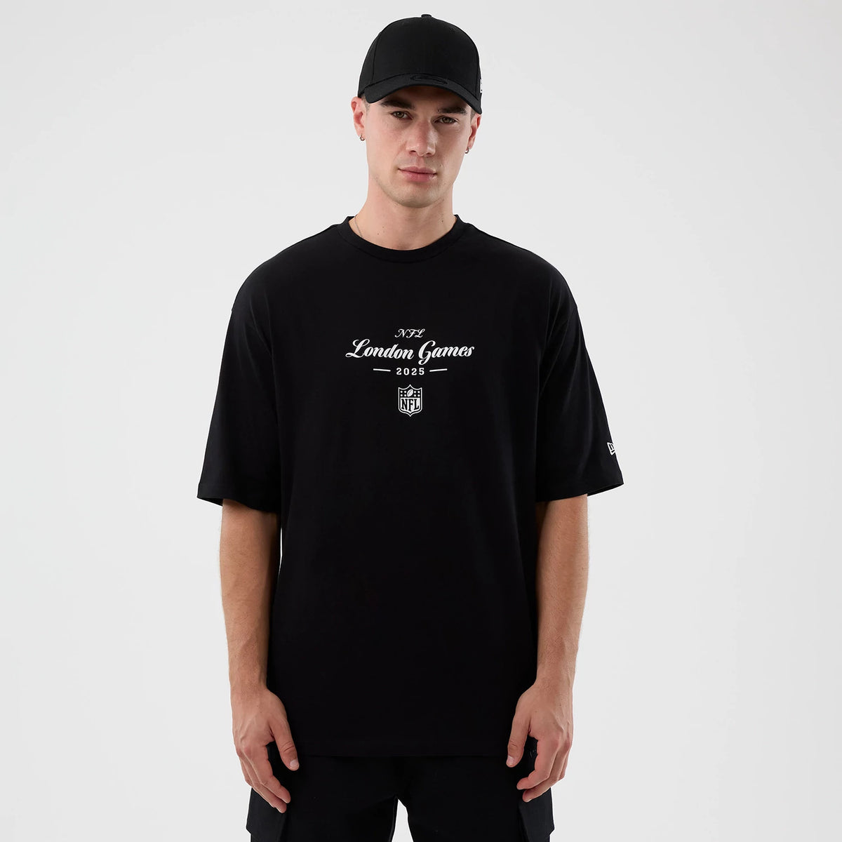 New Era London Games NFL International Series Games Black Oversized T-Shirt, front view on-model showing the white printed London Games 2025 graphic on the chest and an embroidered New Era logo on the left sleeve.