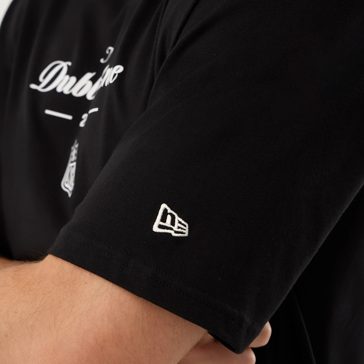 New Era Dublin Game NFL International Series Games Black Oversized T-Shirt, front view showing the white printed Dublin text across the chest, an NFL logo beneath it, and a raised New Era logo embroidered on the lower sleeve.