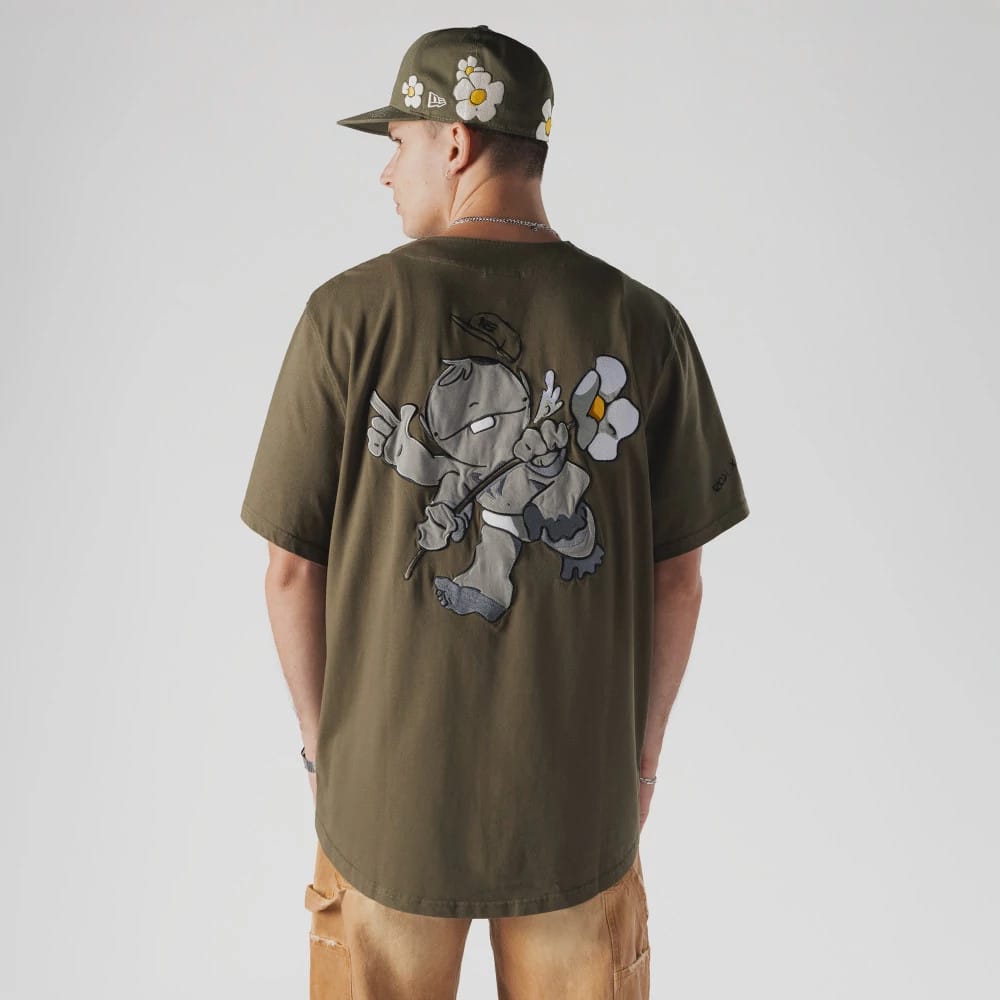 New Era x Rodrigo Roji Flower Green Jersey, back view on a model with a matching cap, featuring a large graphic of a character holding a flower in contrasting grey and white tones, with the New Era flag logo on the left sleeve.