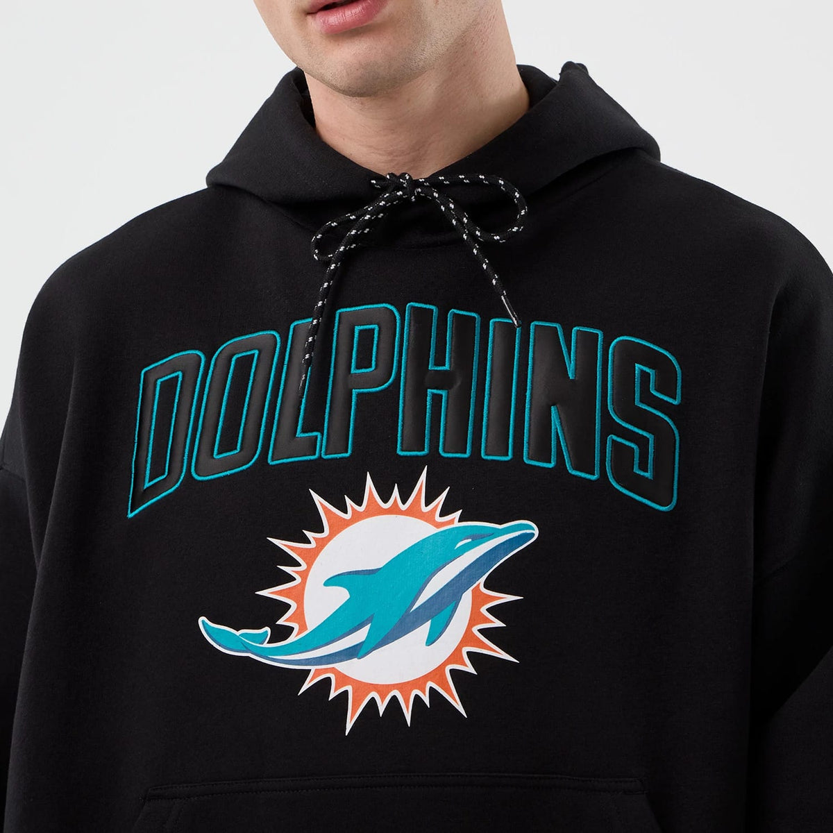 New Era Miami Dolphins NFL International Series Games Black Pullover Hoodie, front view showing large printed DOLPHINS lettering in teal and a dolphin logo beneath, with drawstring detail on the hood.