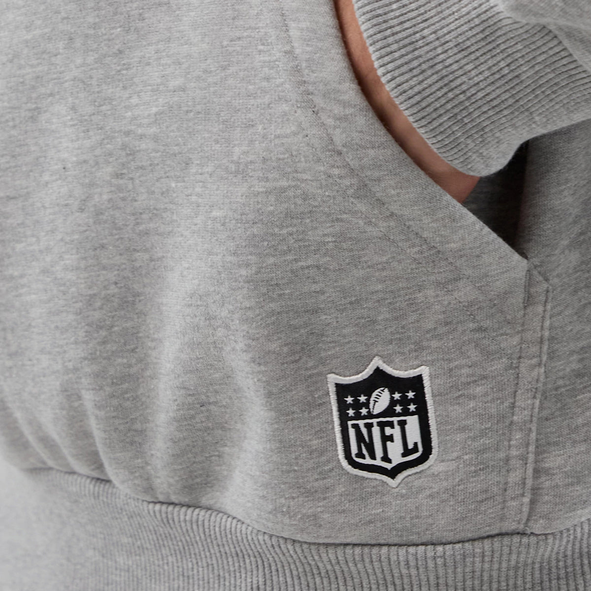 New Era Indianapolis Colts NFL International Series Games Grey Pullover Hoodie, side view showing a close-up of the grey fabric with a ribbed cuff and a white embroidered NFL logo near the lower front pocket.