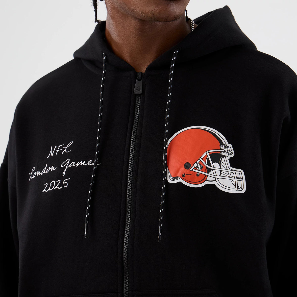 New Era Cleveland Browns NFL International Series Games Black Full Zip Hoodie, front view showing an orange and white printed helmet on the chest, white embroidered NFL London Games 2025 text.