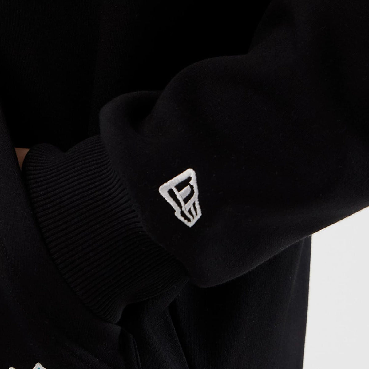 New Era Jacksonville Jaguars NFL International Series Games Black Full Zip Hoodie, side view showing a close-up of the black sleeve with an embroidered white New Era logo near the ribbed cuff.