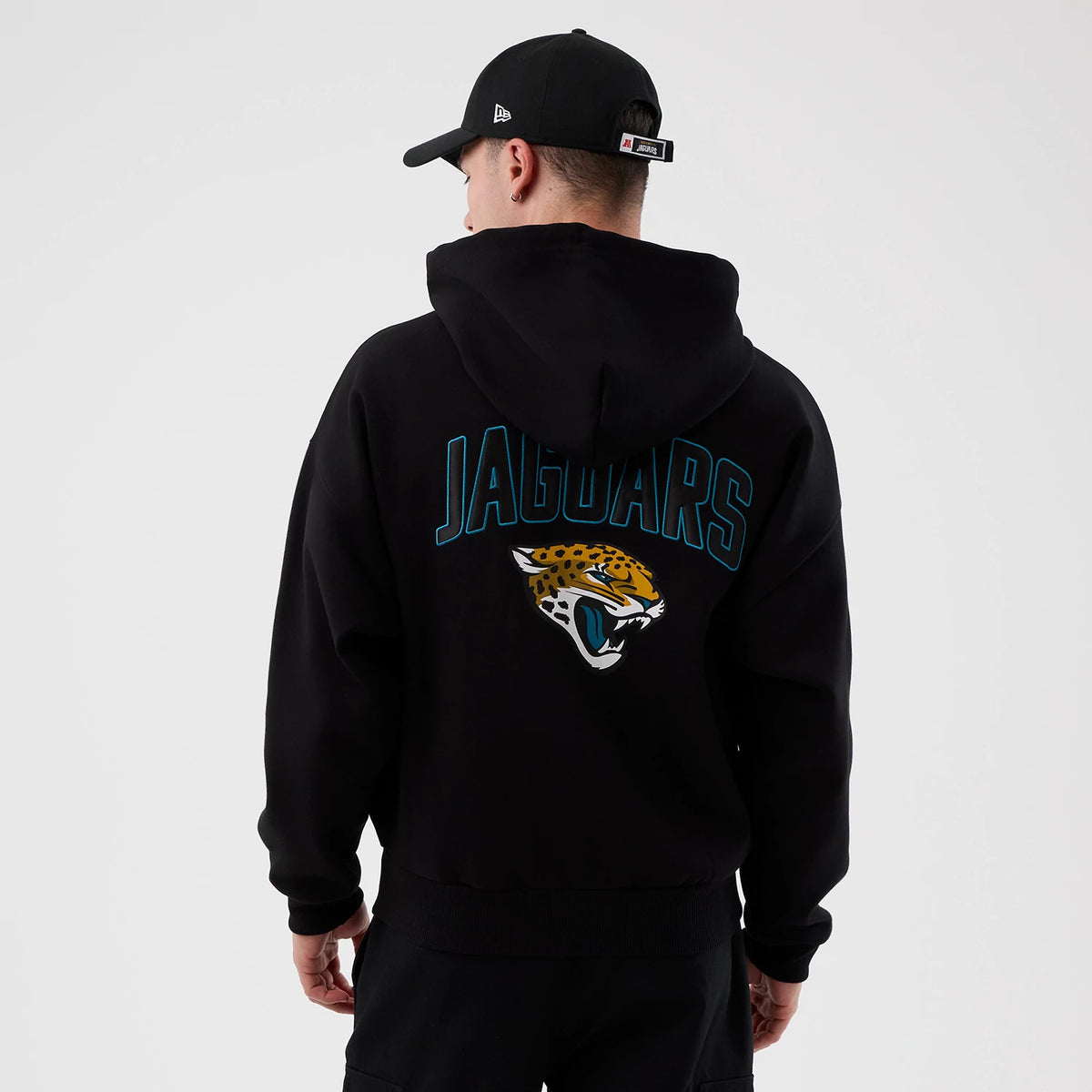 New Era Jacksonville Jaguars NFL International Series Games Black Full Zip Hoodie, back view on a model wearing a dark cap, displaying a teal JAGUARS lettering arching over an embroidered jaguar logo in the centre of the upper back.