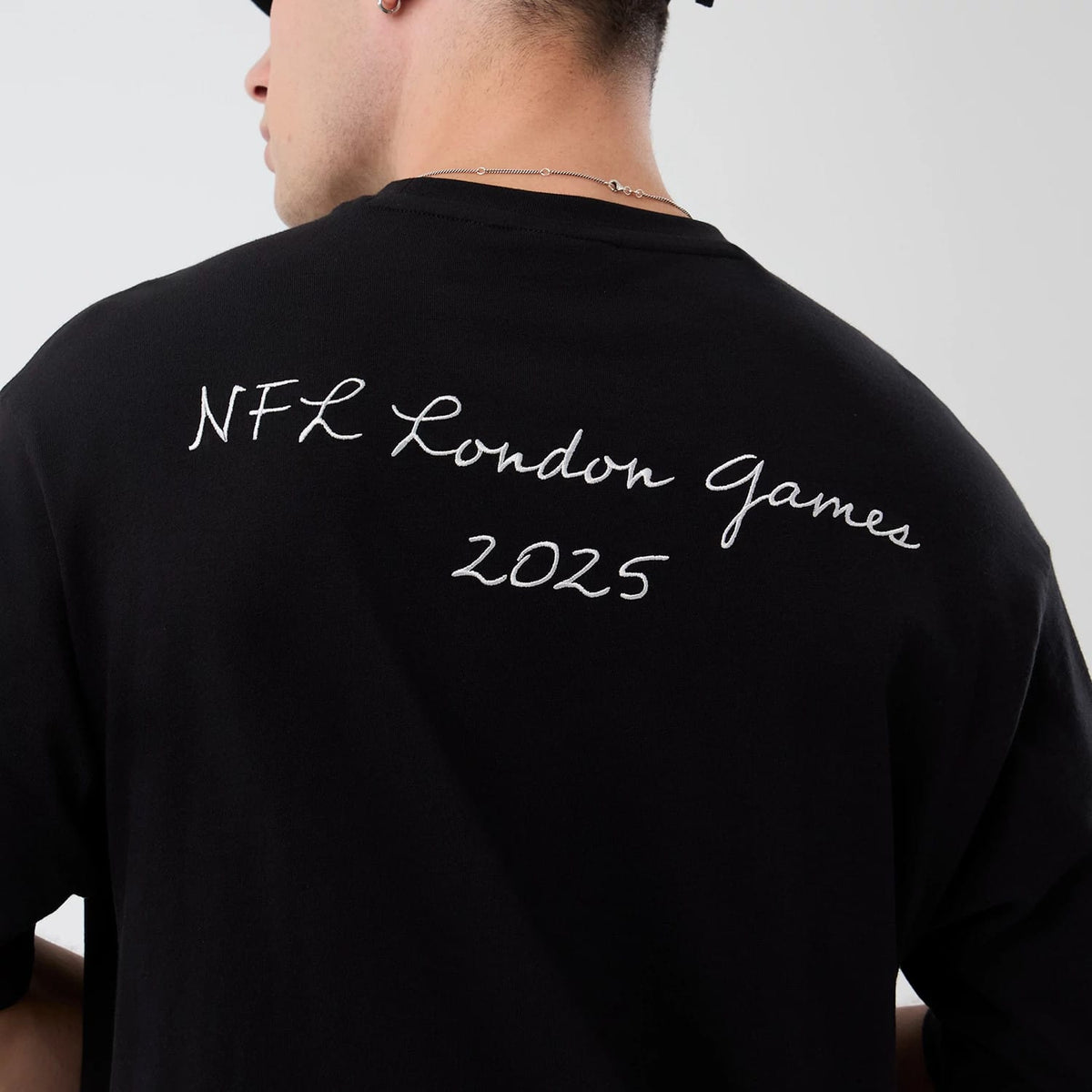 New Era Jaguars NFL International Series Games Script Black Oversized T-Shirt, back view on-model displaying the embroidered white lettering NFL London Games 2025 across the upper back, adding a unique touch to the plain black design.