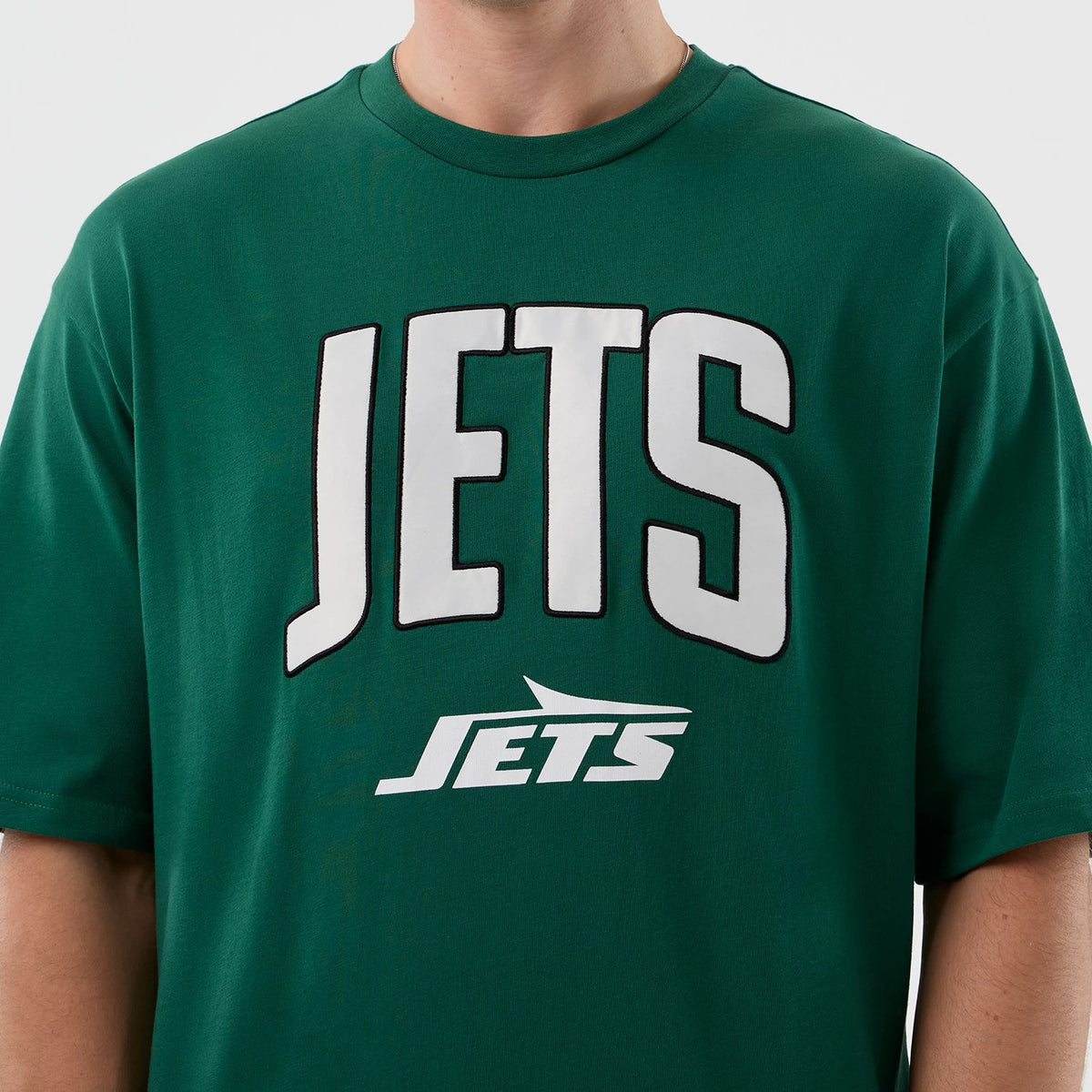 New Era New York Jets NFL International Series Games Green Oversized T-Shirt, front view with large white Jets lettering centred on the green fabric and smaller Jets logo underneath, worn by a model.