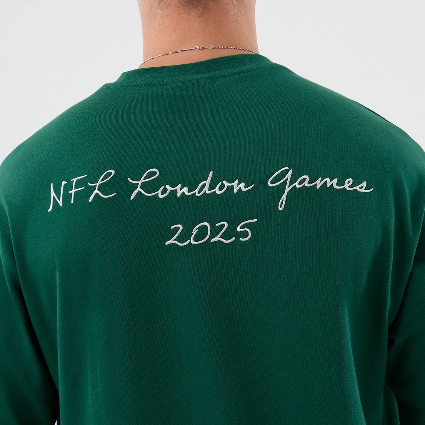 New Era New York Jets NFL International Series Games Green Oversized T-Shirt, back view showing the white embroidered text NFL London Games 2025 across the upper back, worn by a model with a simple chain necklace.