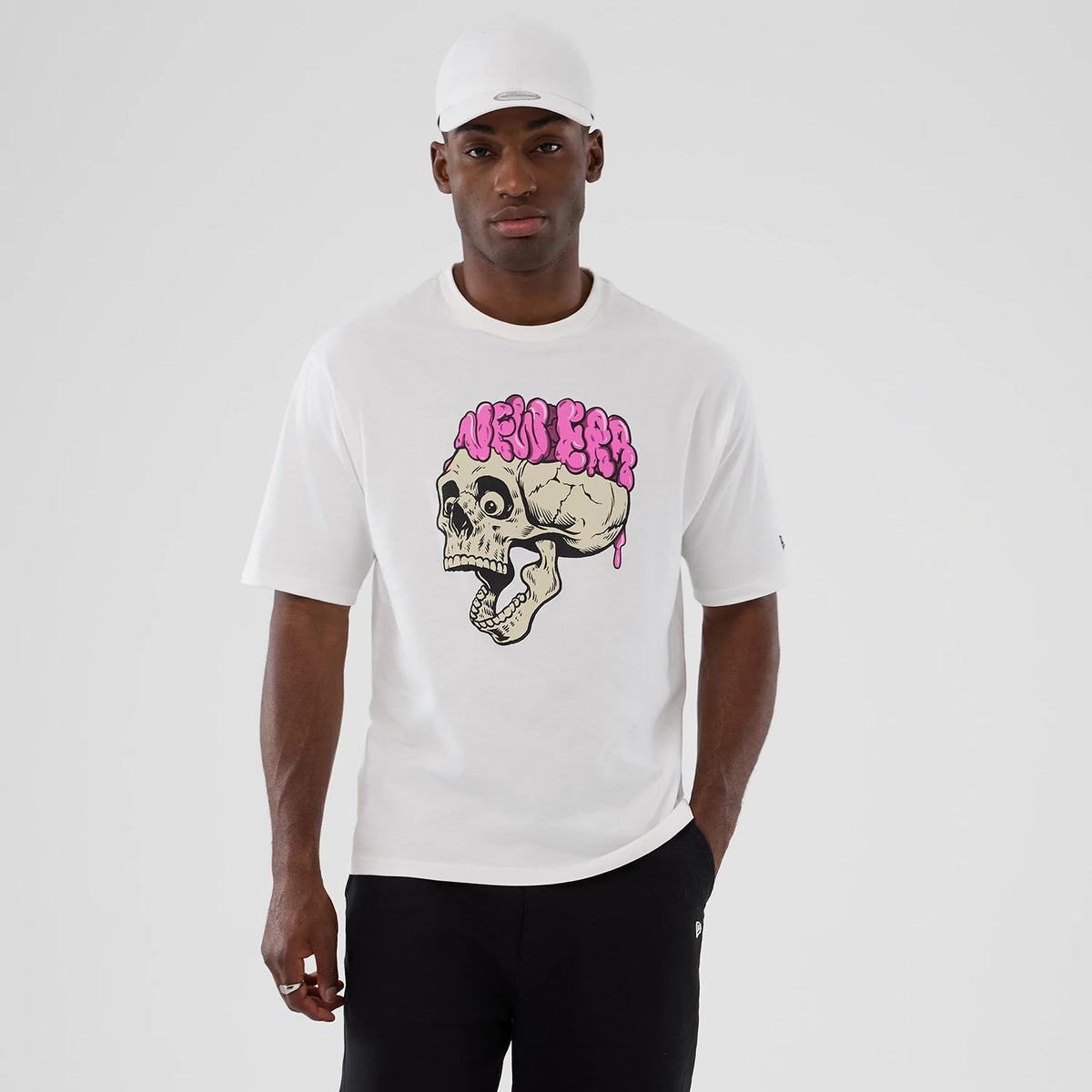 New Era Halloween Skull Graphic White Oversized T-Shirt, front view on-model featuring a large central skull graphic with pink New Era lettering dripping above it, short sleeves, and a small embroidered New Era logo on the left sleeve.