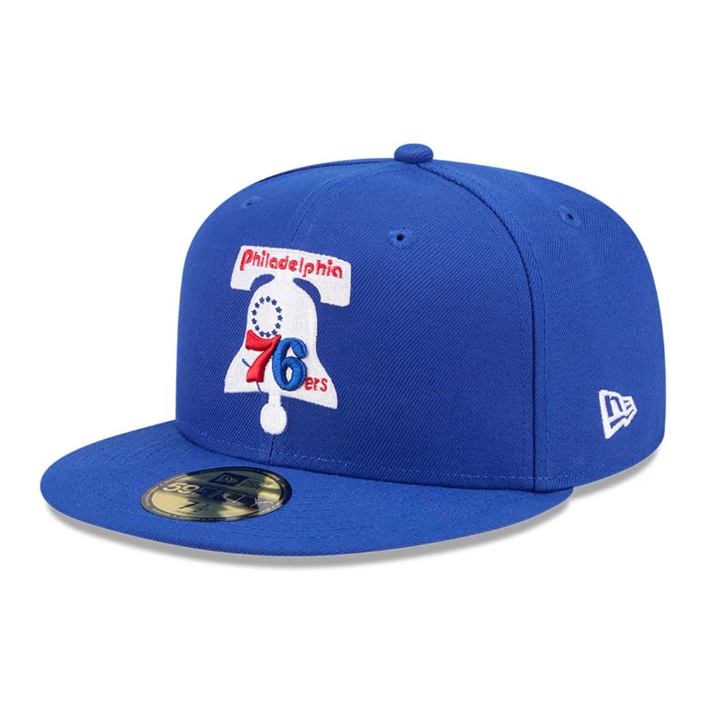 Philadelphia 76ers NBA Hardwood Classic Blue New Era 59FIFTY Fitted Cap, three-quarter view showing the red, white, and blue Liberty Bell logo embroidered on the front panel, with a gold 59FIFTY size sticker on the flat blue visor.
