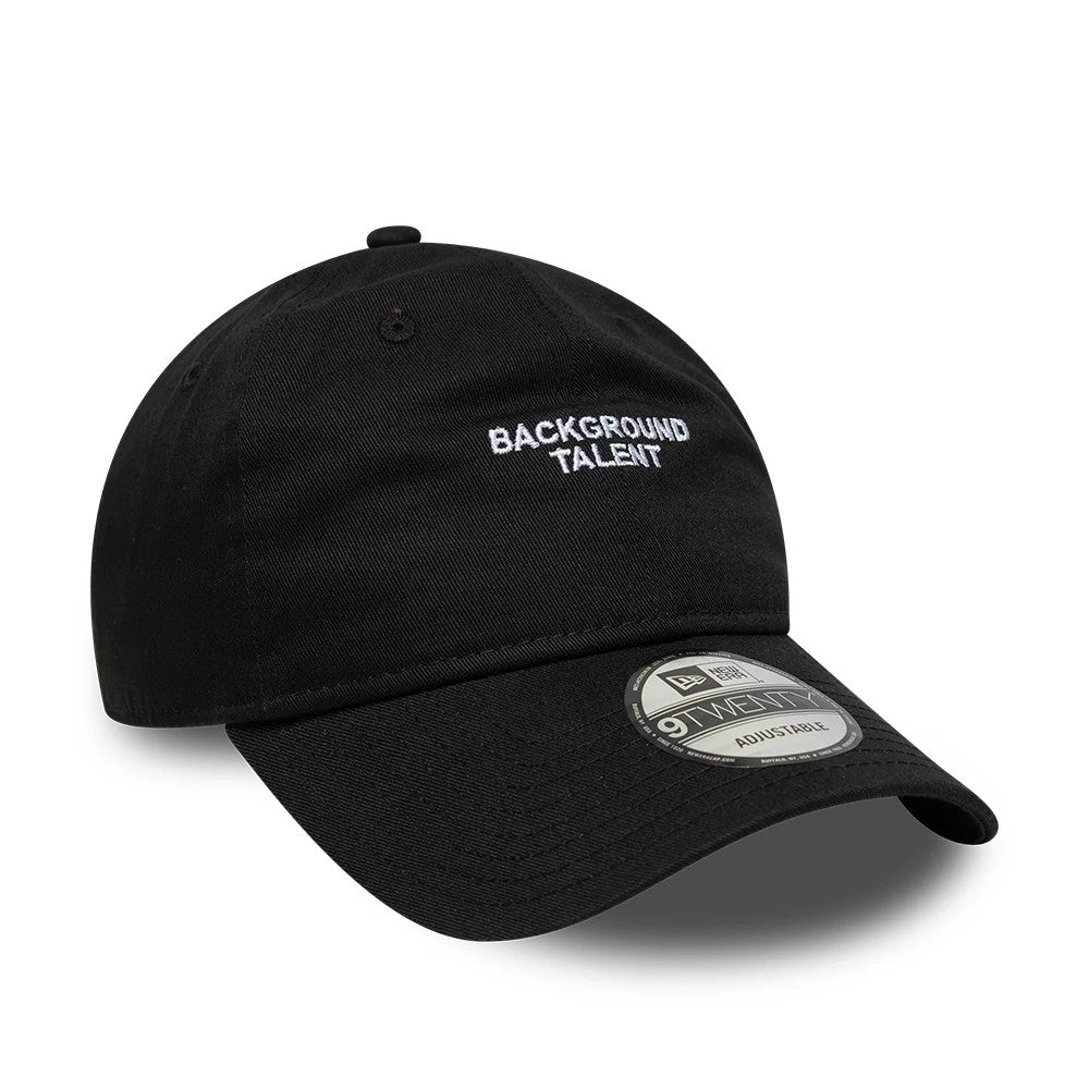 New Era Slogan Background Talent Black 9TWENTY Adjustable Cap, front view showing white embroidered slogan on the unstructured black crown, a curved visor with a 9TWENTY size sticker, and black top button.