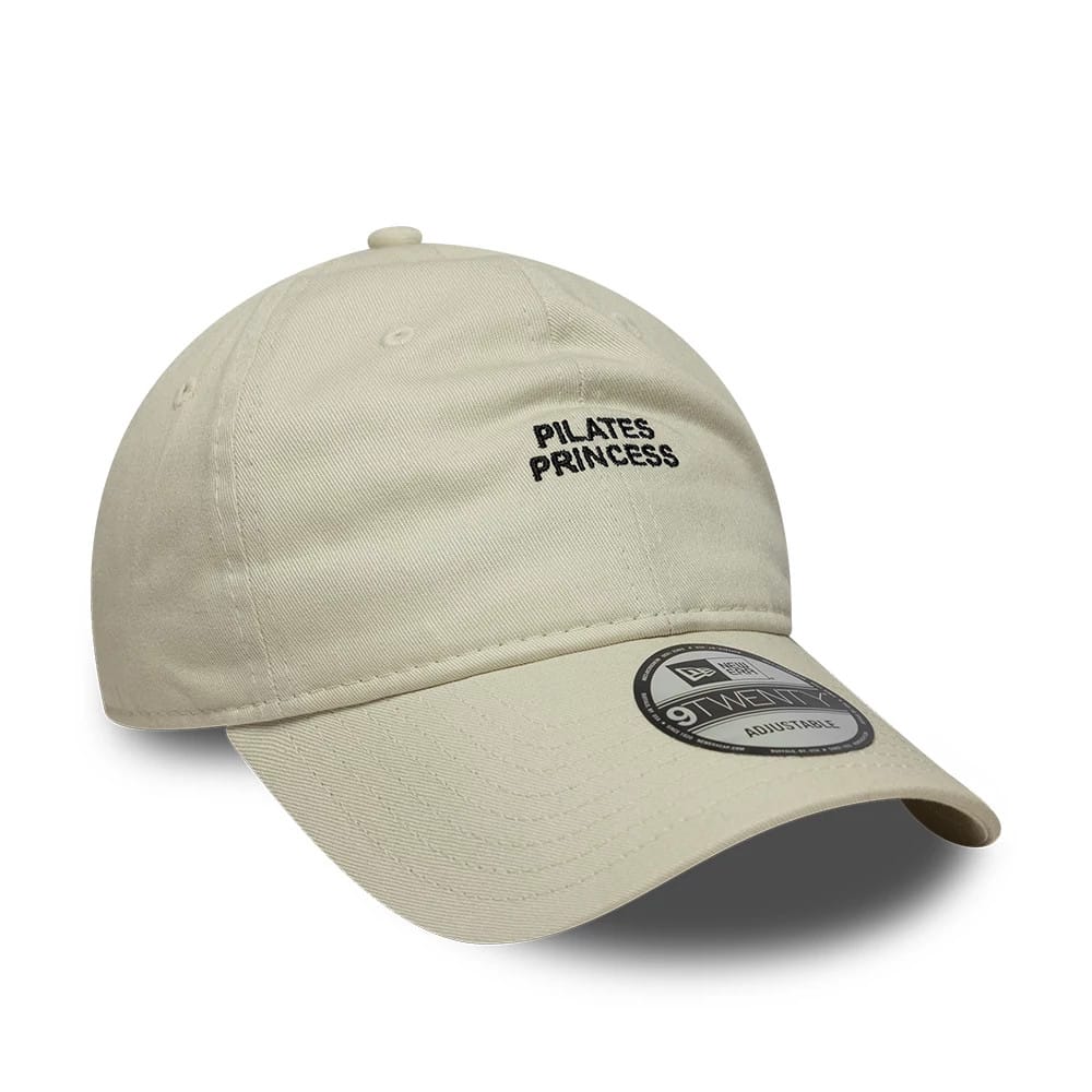 New Era Slogan Pilates Princess Light Beige 9TWENTY Adjustable Cap, three-quarter view showing the black embroidered Pilates Princess lettering on the front panel, with a light beige pre-curved visor and a 9TWENTY size sticker.