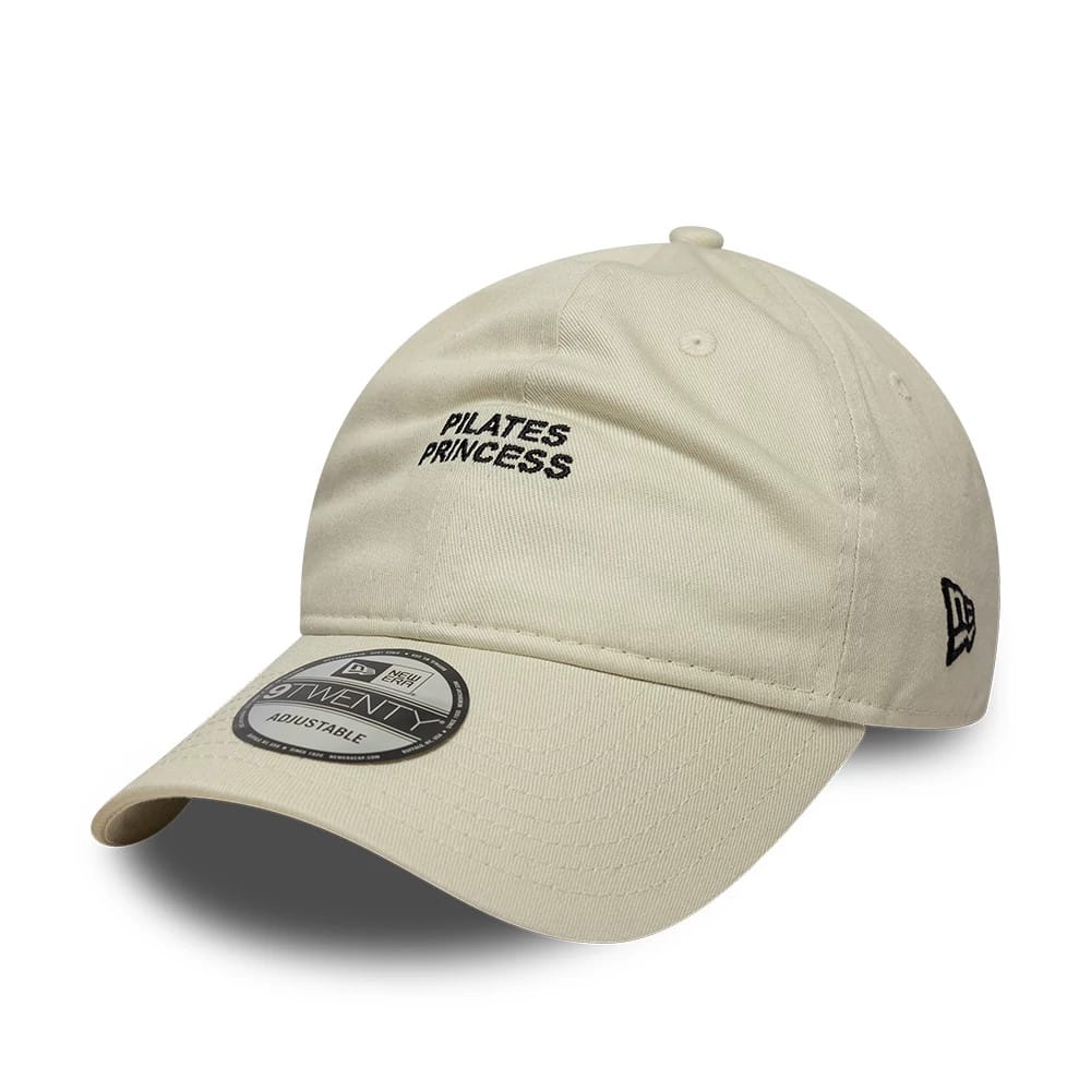 New Era Slogan Pilates Princess Light Beige 9TWENTY Adjustable Cap, three-quarter view showing the black Pilates Princess embroidery on the front panel, with a curved visor and a 9TWENTY size sticker on the visor.