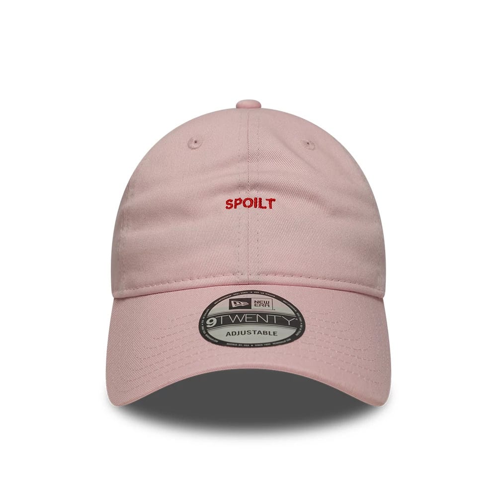 New Era Slogan Spoilt Pastel Pink 9TWENTY Adjustable Cap, front view showing the red embroidered Spoilt text on the unstructured pastel pink crown, curved visor with 9TWENTY size sticker, and top button.