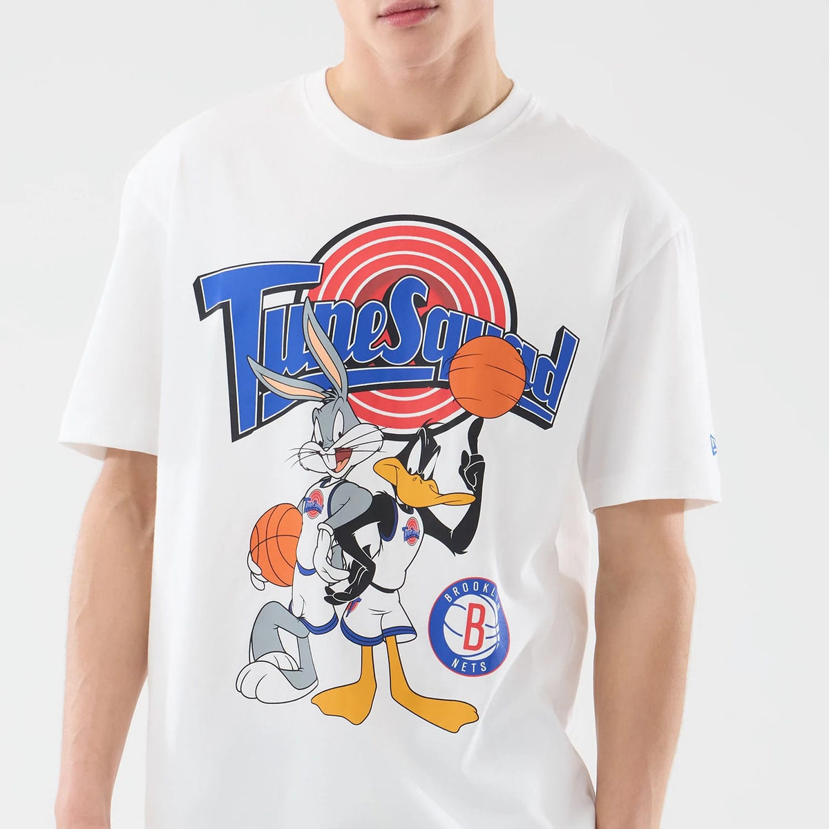 New Era Brooklyn Nets Space Jam 2 X NBA White T-Shirt, front view showing Bugs Bunny and Daffy Duck graphic holding basketballs, large blue Tune Squad script across the chest, with a small printed Brooklyn Nets logo near the hem.