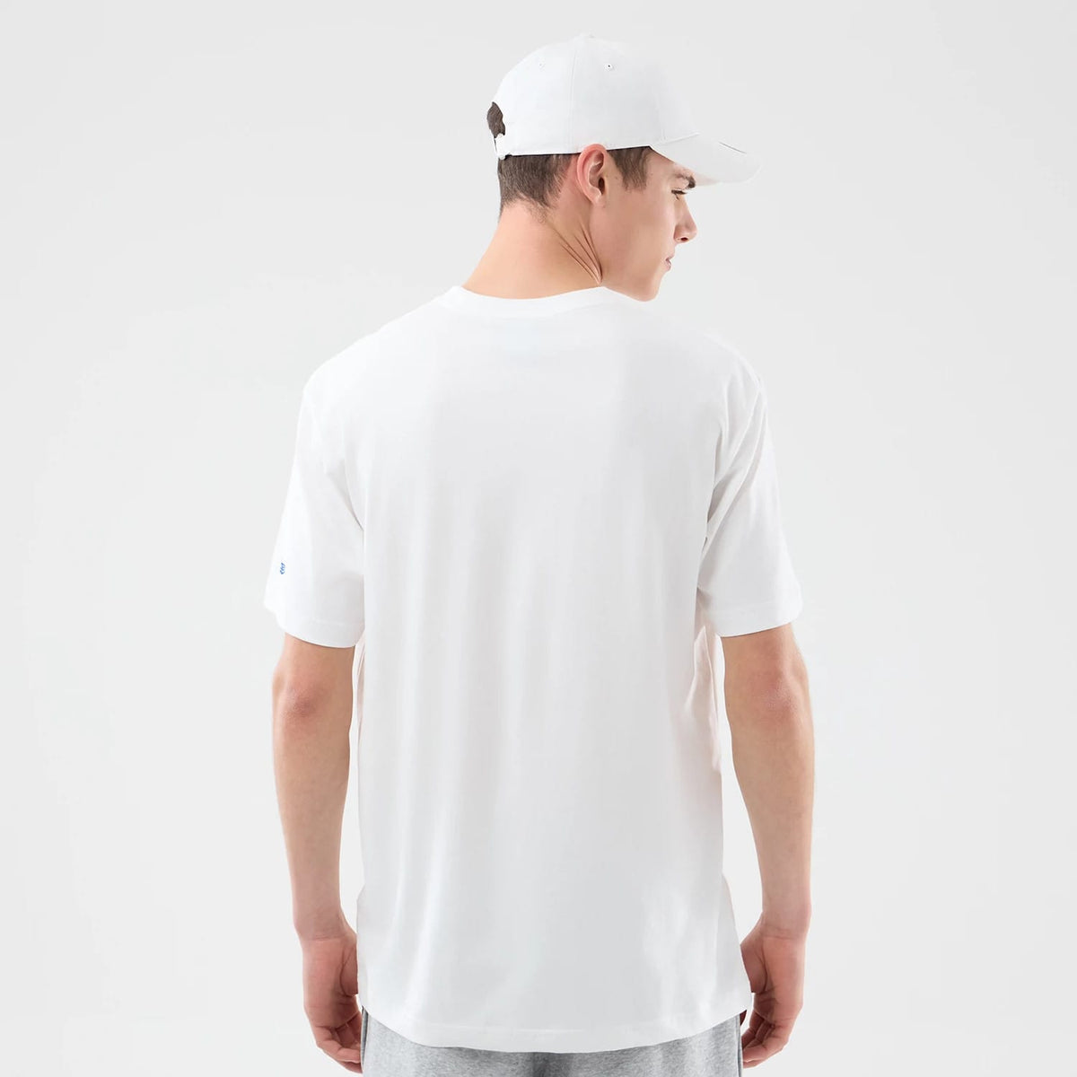 New Era New York Knicks Space Jam 2 X NBA White T-Shirt, back view on-model showcasing a plain white back with a small printed New Era logo on the left sleeve, paired with a plain white cap.
