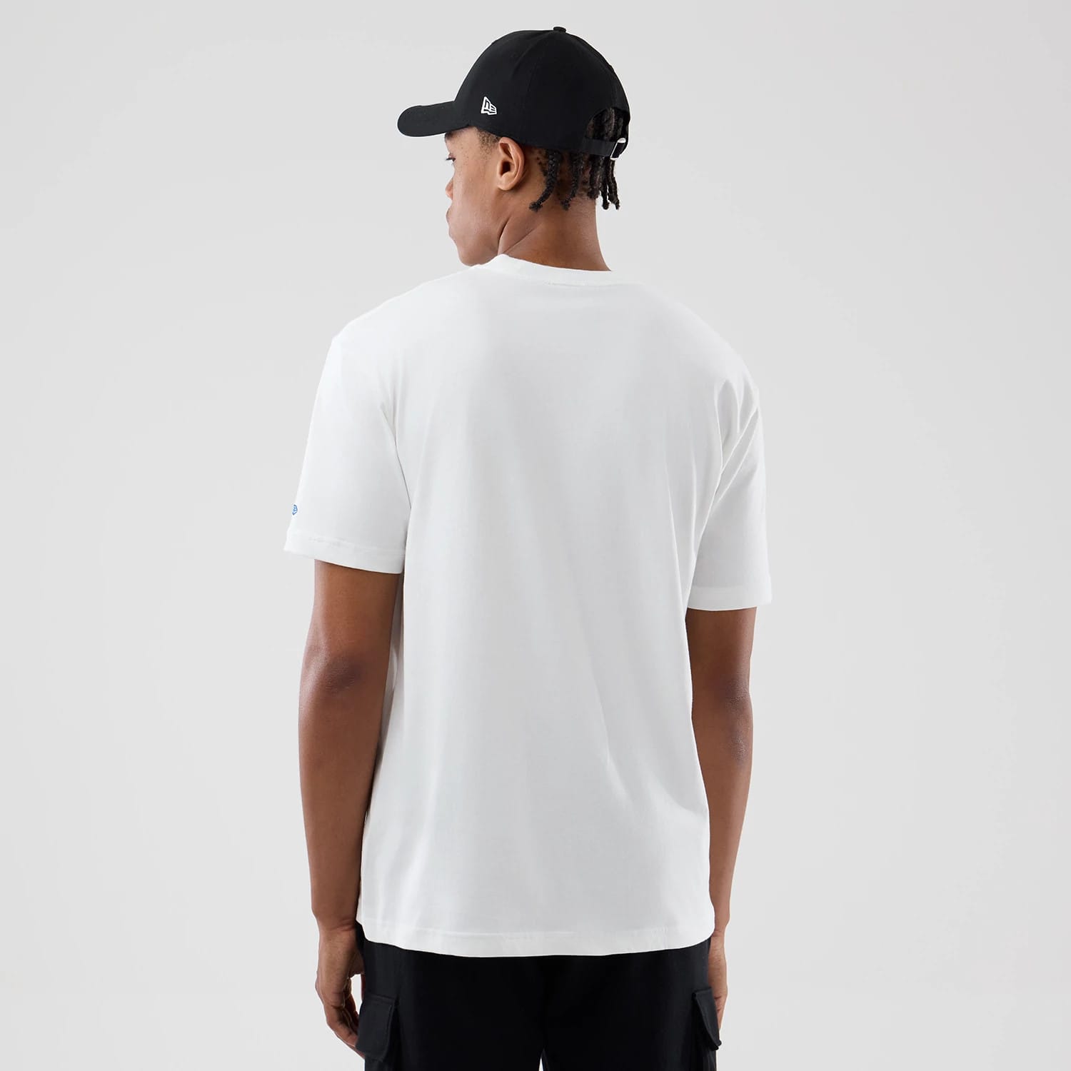 New Era LA Lakers Space Jam 2 X NBA White T-Shirt, back view showing the plain white shirt on-model with a small blue embroidered logo on the sleeve, styled with a black cap worn by the model facing away.