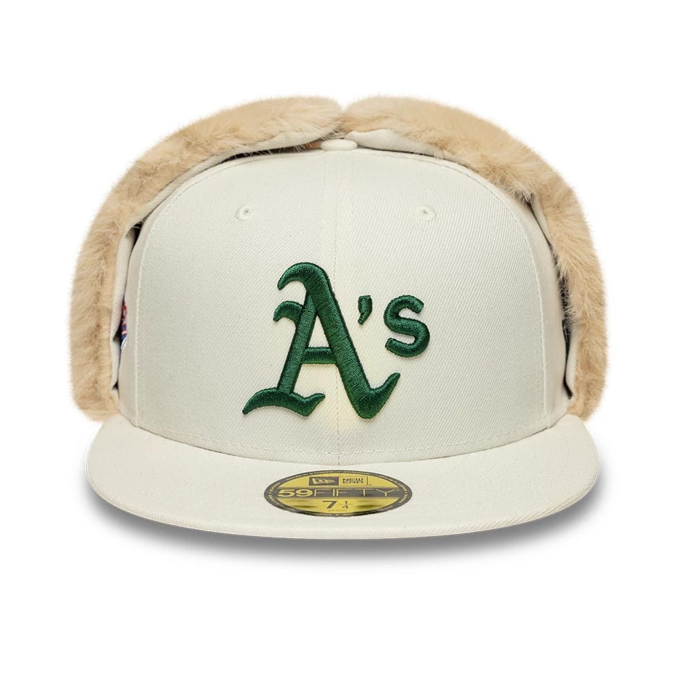 Athletics MLB World Series Cream Dogear New Era 59FIFTY Fitted Cap, front view showing the raised green embroidered Athletics logo on the cream front panel, with furry dogear flaps, a flat cream visor, and a gold 59FIFTY size sticker.