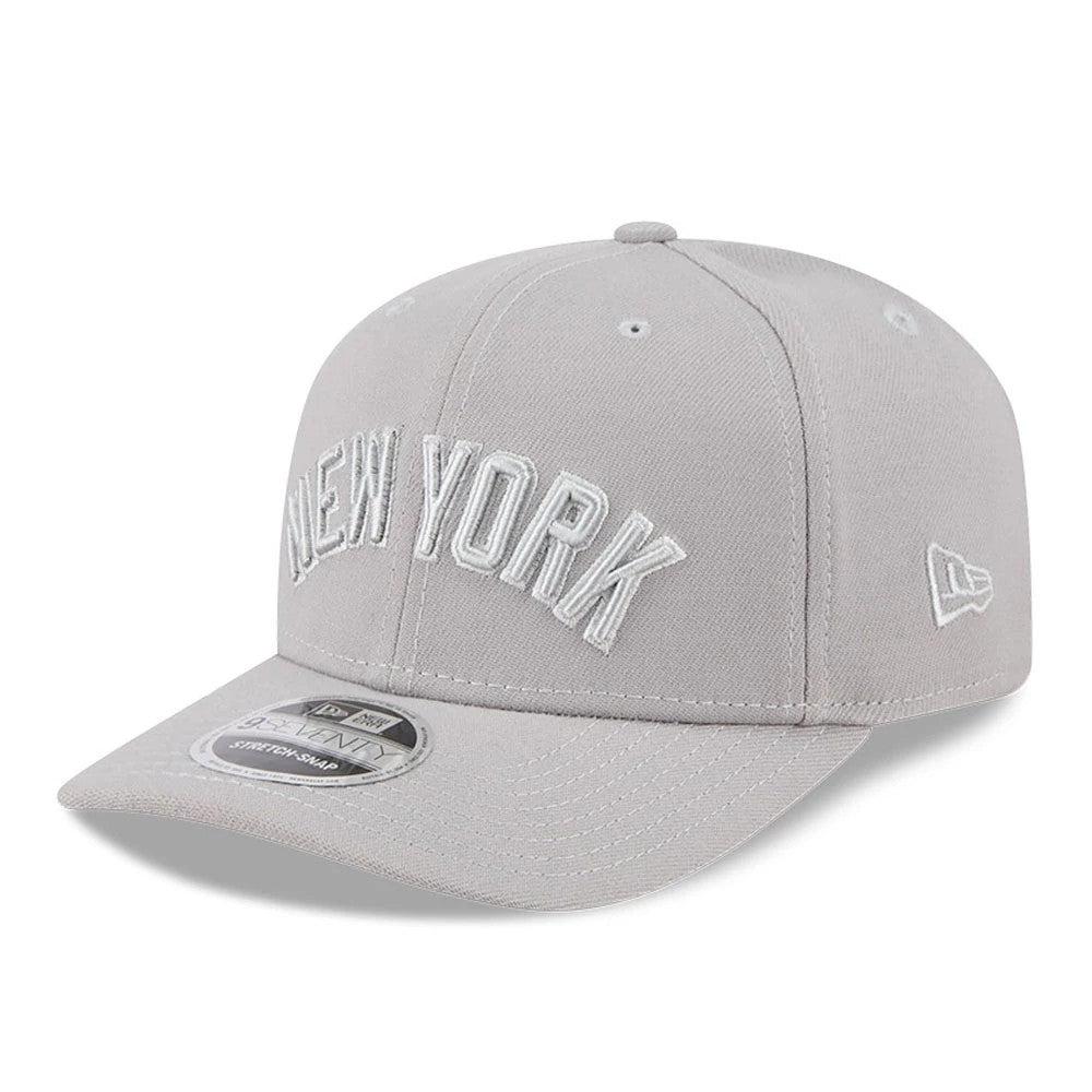 New York Yankees MLB Script Grey New Era 9SEVENTY Stretch Snap Adjustable Cap, three-quarter view showing the white raised embroidered New York lettering on the structured grey crown, curved grey visor and the 9SEVENTY size sticker.