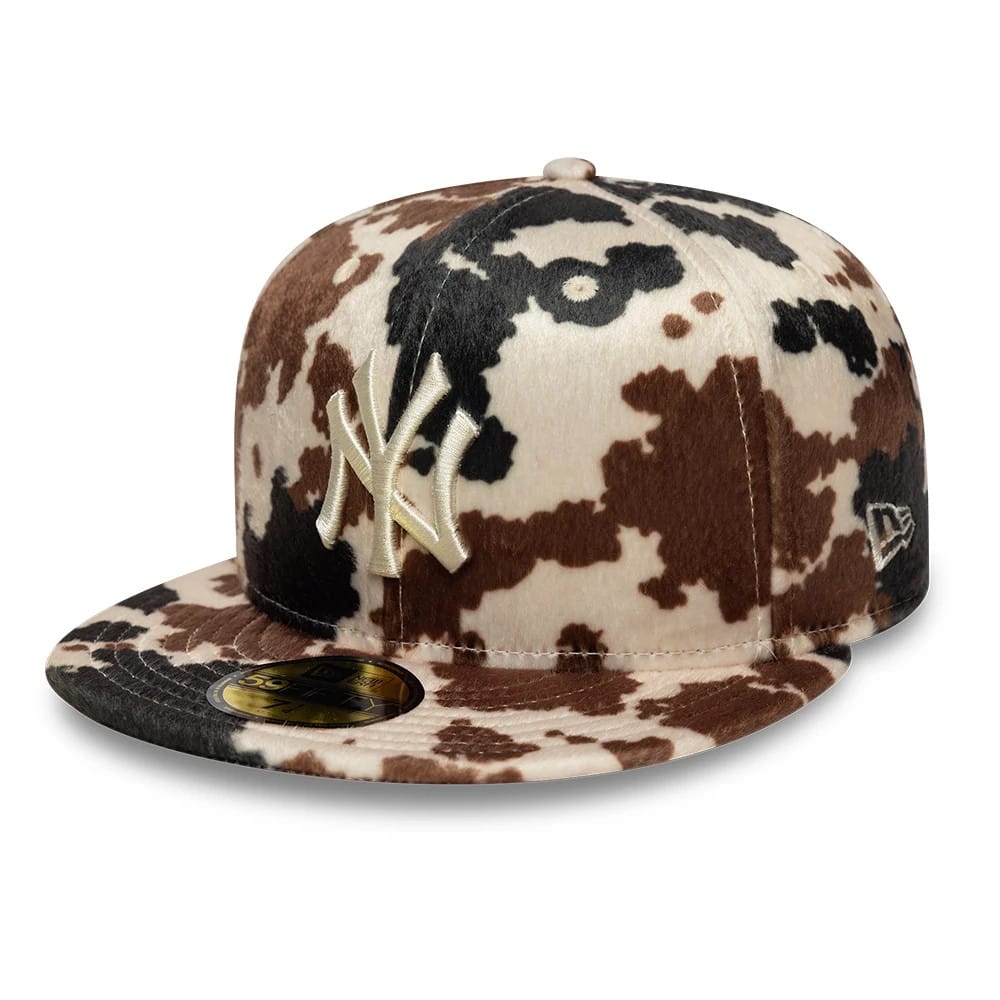 New York Yankees Animal Print Cow Beige New Era 59FIFTY Fitted Cap, three-quarter view showing a raised beige NY logo embroidered on a cow print pattern with a flat visor and a gold 59FIFTY size sticker on the front.