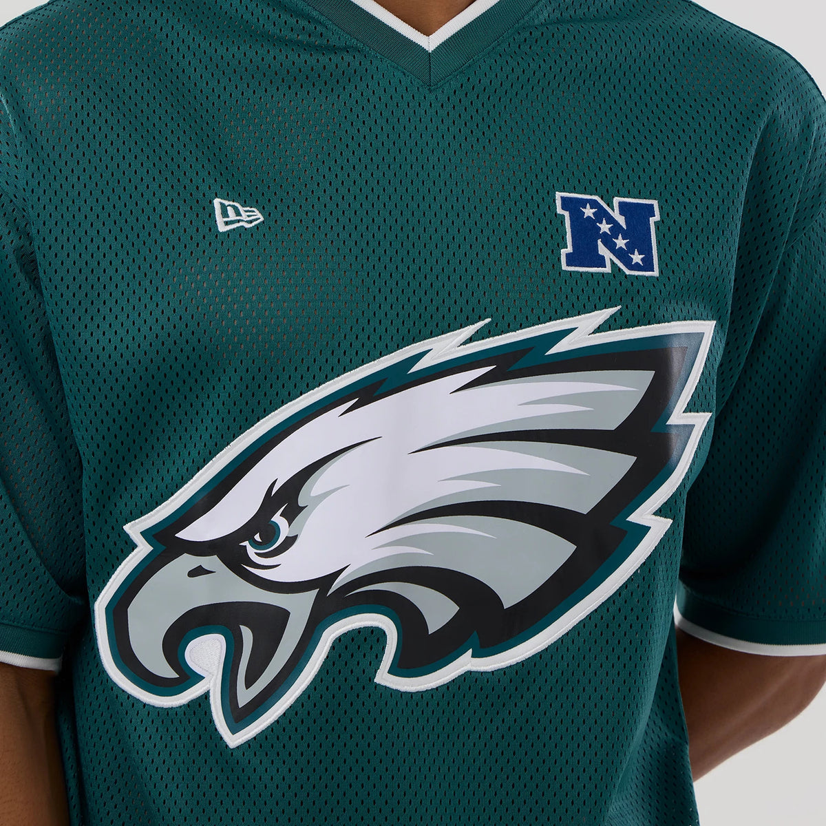 New Era Philadelphia Eagles NFL Mesh Dark Green Oversized T-Shirt, front view showing the large printed team eagle logo across the chest, a small embroidered New Era logo on the left shoulder, and a white NFC patch on the right shoulder.