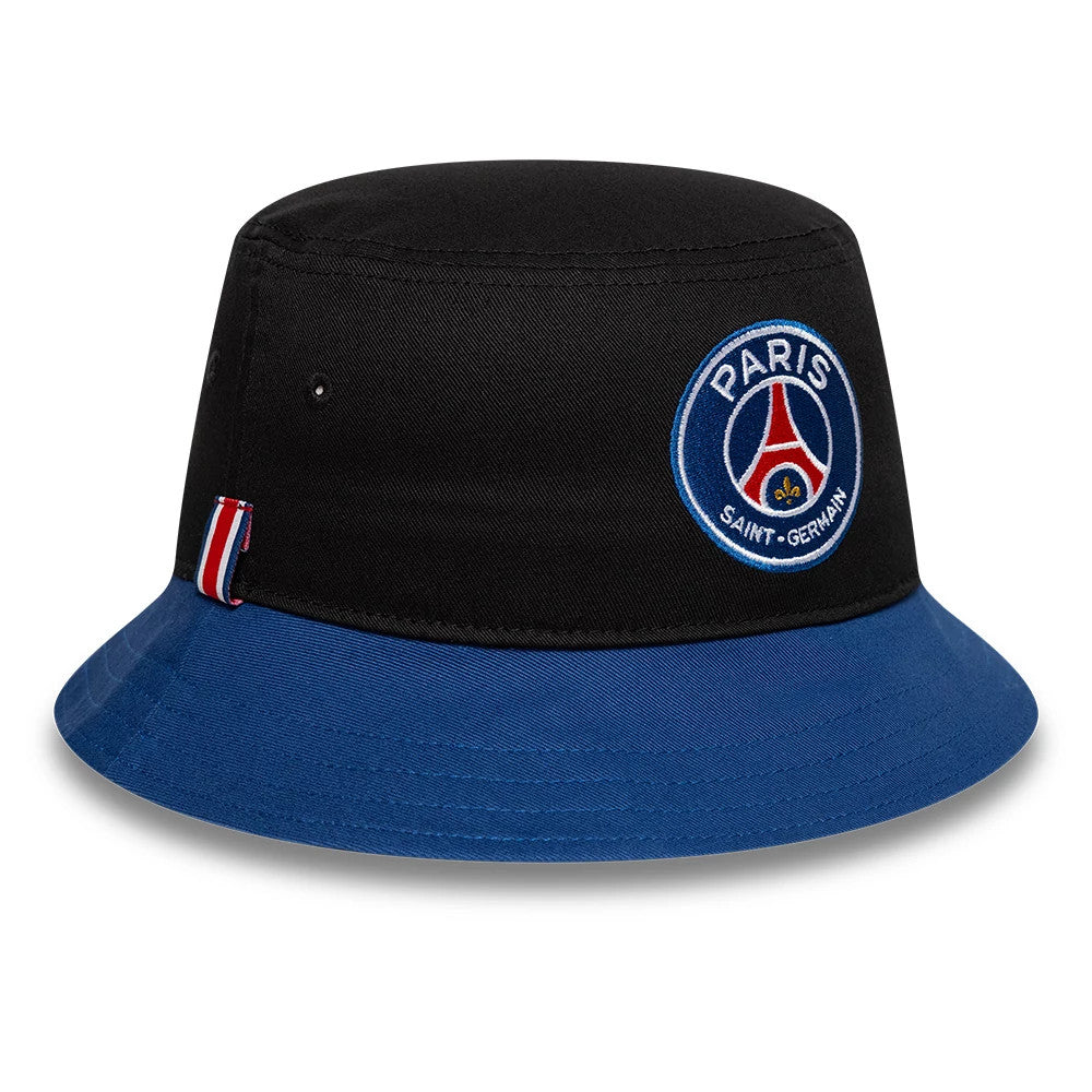 New Era Paris Saint-Germain Core Black Bucket Hat, front view showing the embroidered Paris Saint-Germain crest on the structured black crown, with blue visor and red-white-red striped tag on the side.