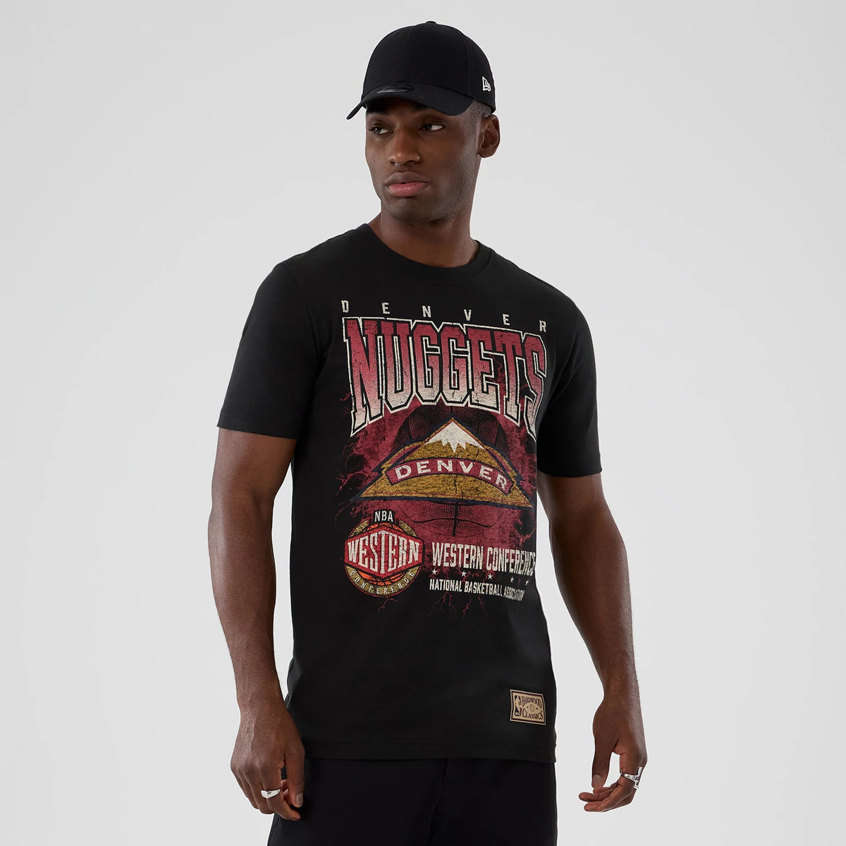 New Era Denver Nuggets NBA Hardwood Classic Black T-Shirt, front view on a model showcasing a large graphic of the Nuggets logo with Western Conference lettering, detailed mountain imagery, and a small patch logo near the hem.