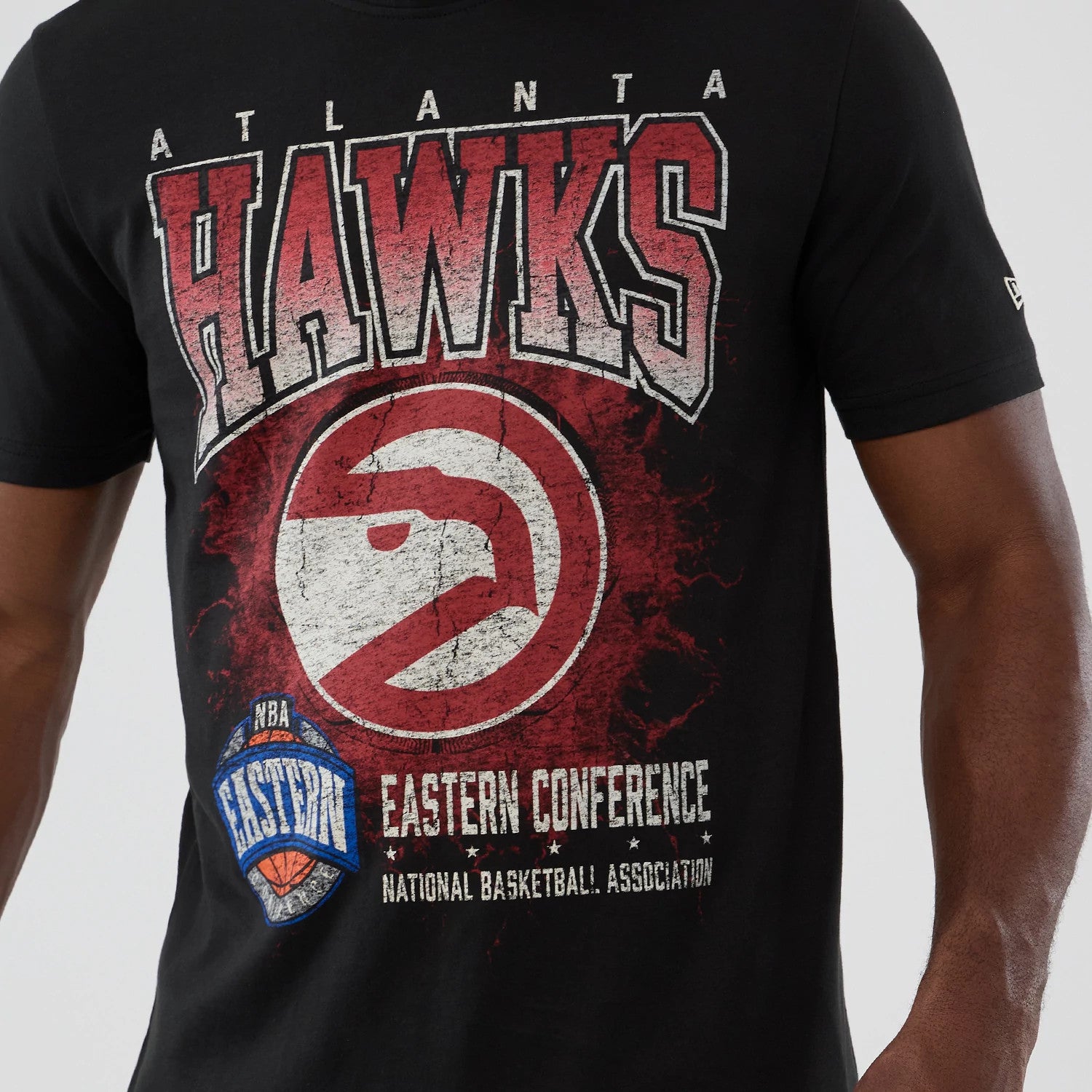 New Era Atlanta Hawks NBA Hardwood Classic Black T-Shirt, front view showing a large distressed Hawks graphic in red and white on the chest, with the Eastern Conference logo below and an embroidered New Era logo on the sleeve.