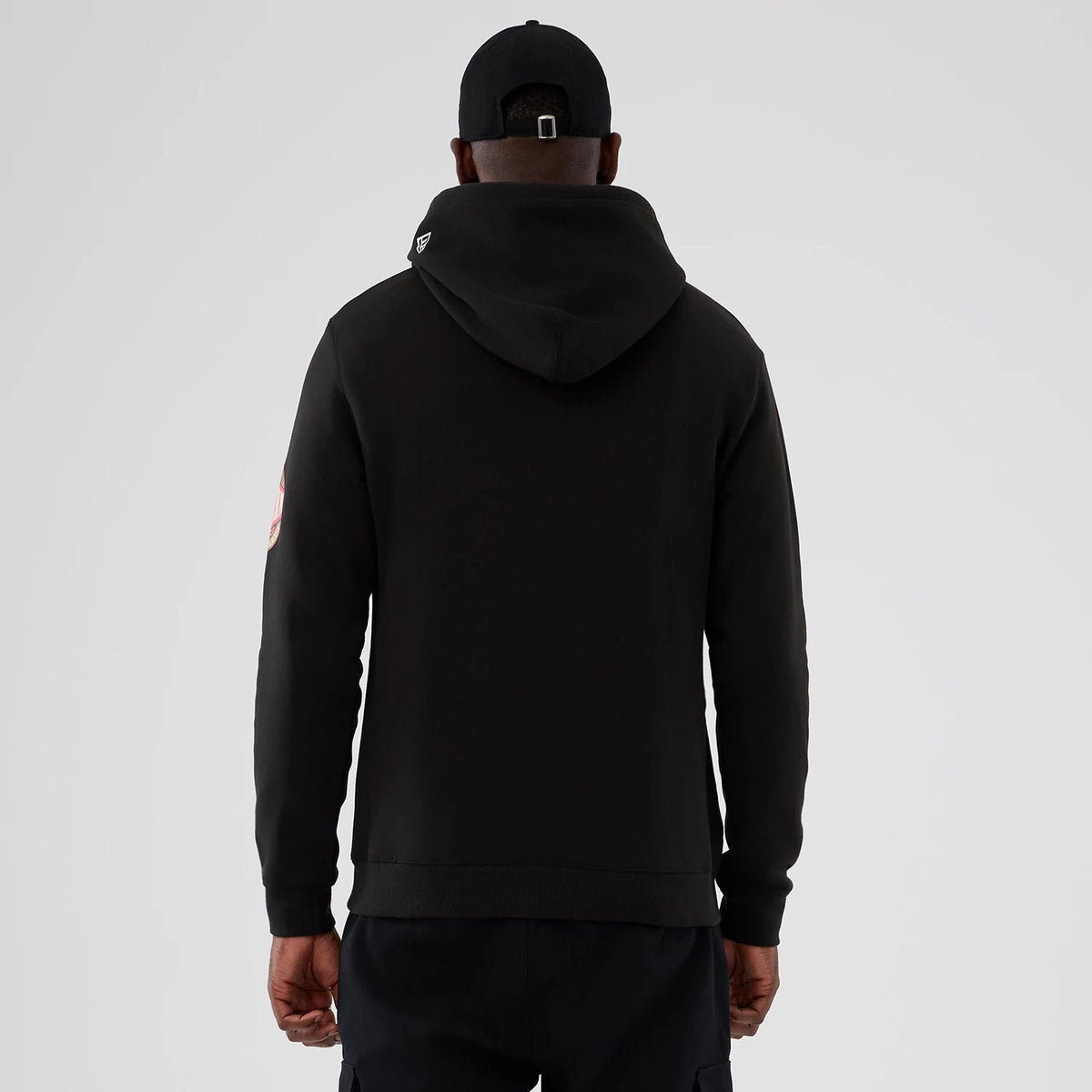 New Era LA Lakers NBA Hardwood Classic Black Pullover Hoodie, back view on a model wearing a matching black cap, showing a small embroidered New Era logo on the hood's edge and a circular team graphic on the sleeve.