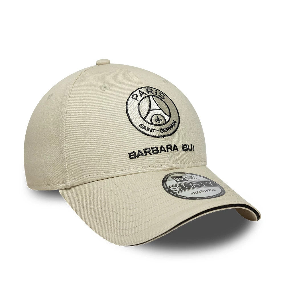 Barbara Bui x Paris Saint-Germain Light Beige New Era 9FORTY Adjustable Cap, three-quarter view showing black embroidered PSG and Barbara Bui logos on structured light beige crown, with curved visor and 9FORTY size sticker.