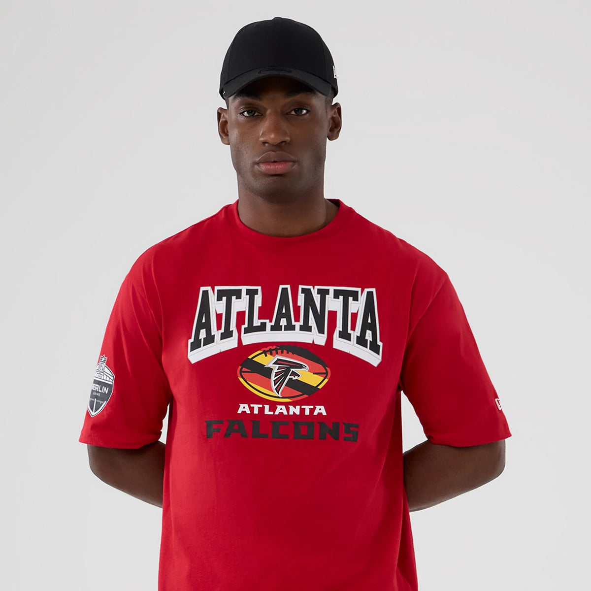New Era Atlanta Falcons NFL International Series Games 2025 Red Oversized T-Shirt, front view on-model showing ATLANTA lettering and team logo printed centrally on the chest with a New Era embroidered logo on the left sleeve.