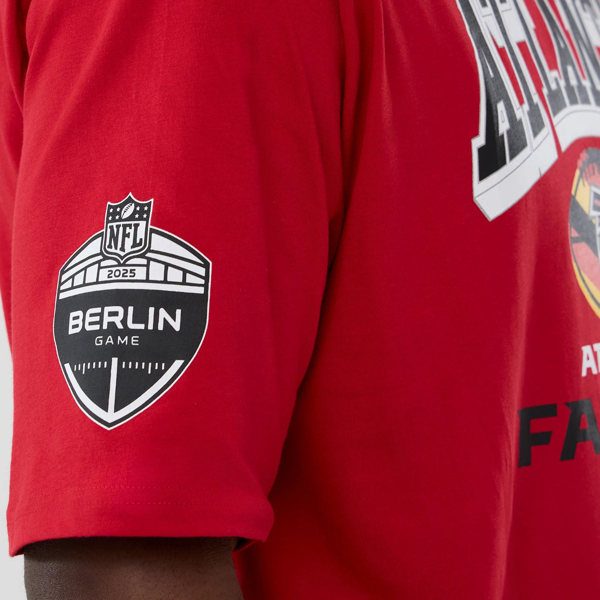 New Era Atlanta Falcons NFL International Series Games 2025 Red Oversized T-Shirt, three-quarter view showing the Berlin Game 2025 printed NFL shield on the sleeve and part of a graphic print across the chest.