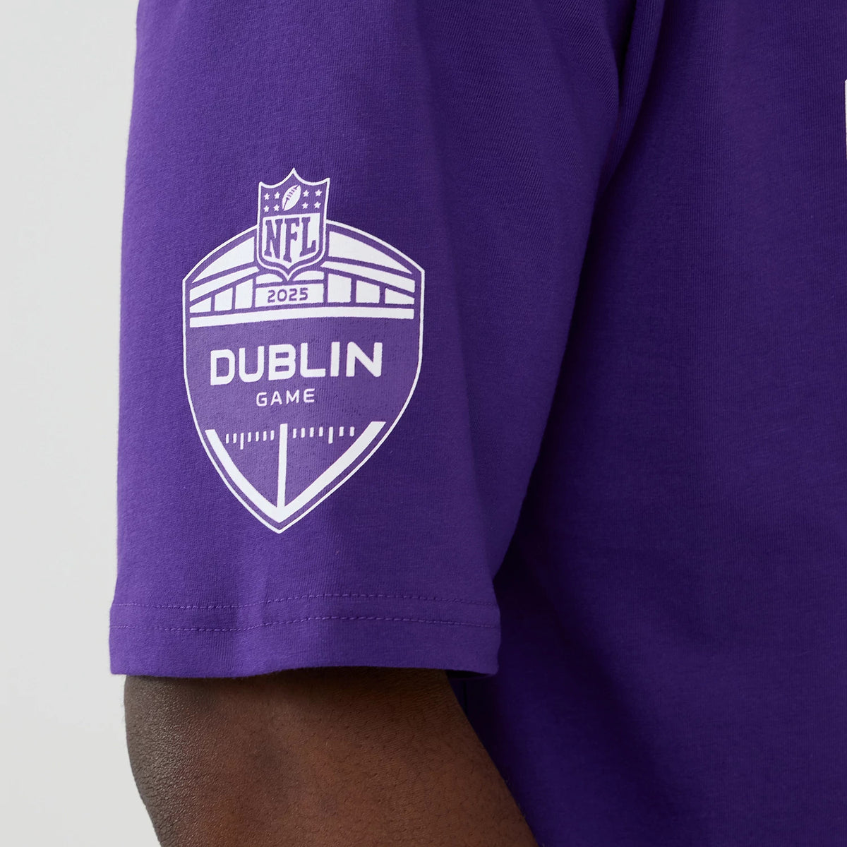 New Era Minnesota Vikings NFL International Series Games 2025 Purple Oversized T-Shirt, side view showing a large white printed Dublin Game 2025 NFL shield logo on the upper sleeve against the purple fabric.