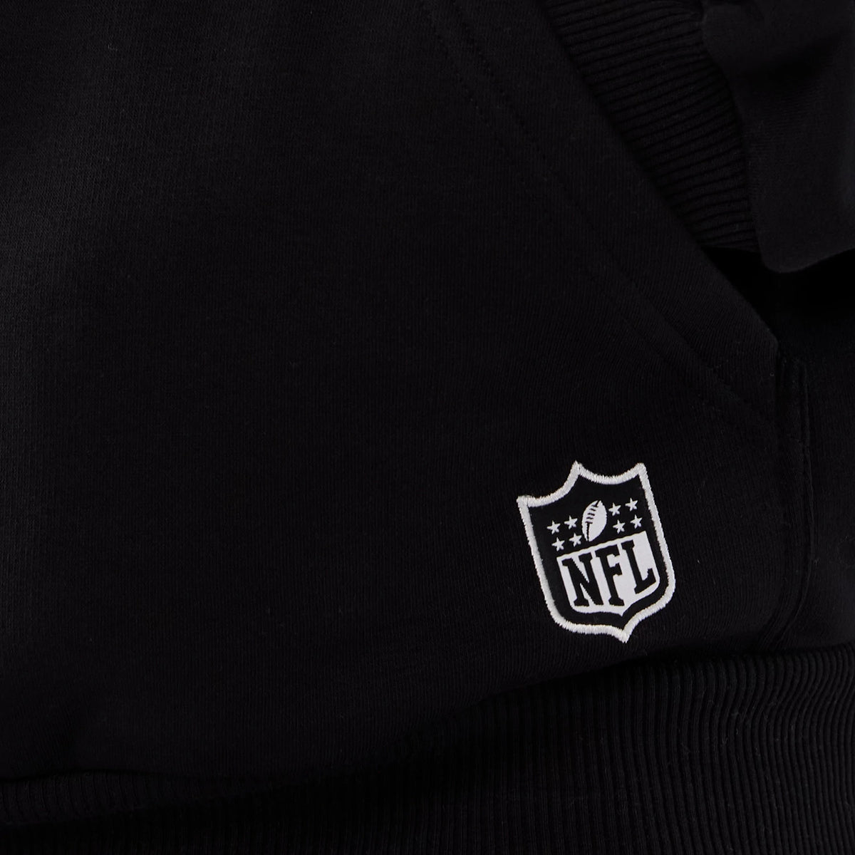 New Era Atlanta Falcons NFL International Series Games 2025 Black Premium Pullover Hoodie, close-up view showing the ribbed hem detail and a white embroidered NFL logo near the lower front.