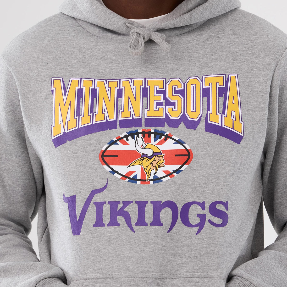 New Era Minnesota Vikings NFL International Series Games 2025 Grey Pullover Hoodie, front view showing yellow and purple Minnesota lettering above a football graphic with a Union Jack and Vikings logo, and purple Vikings text below.