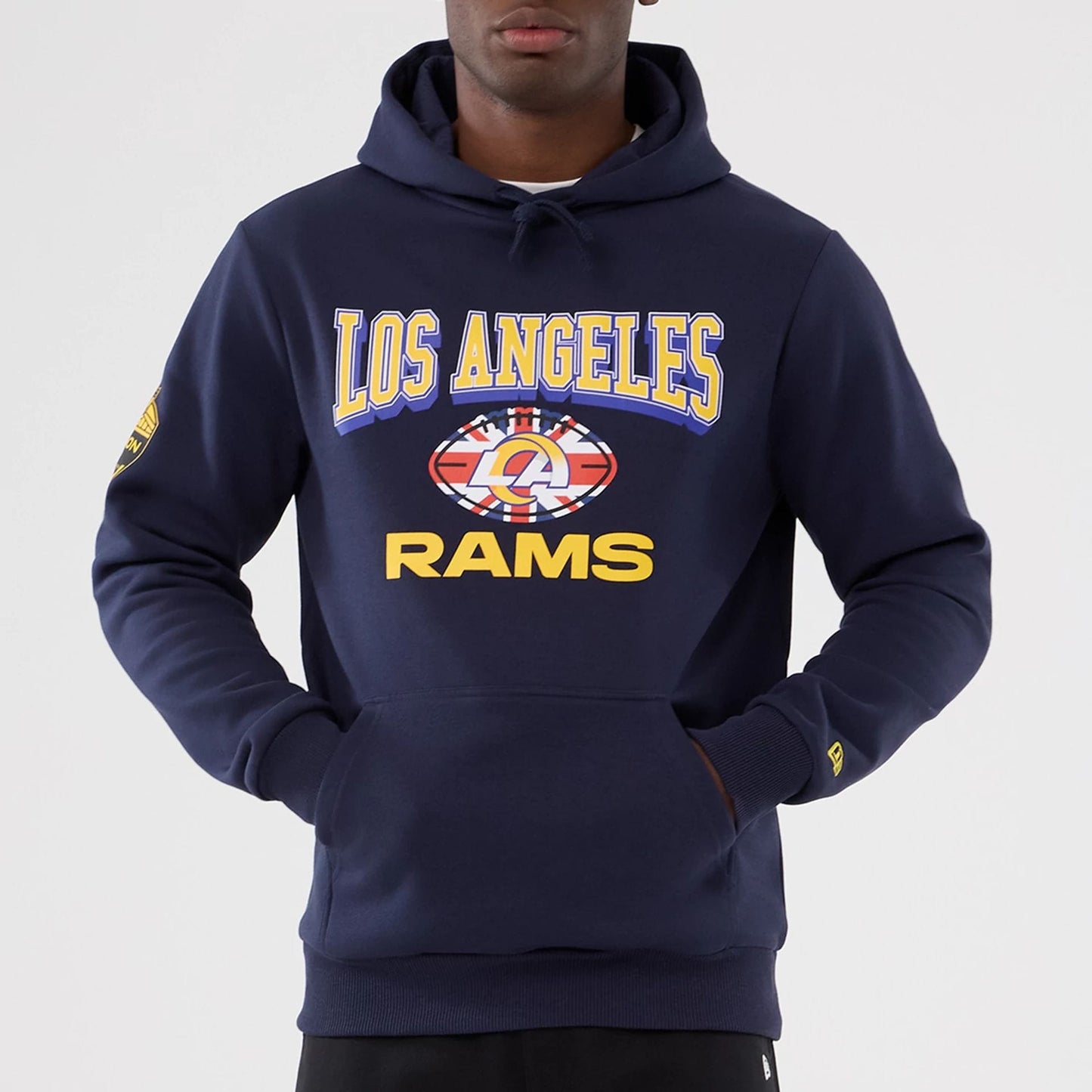 New Era LA Rams NFL International Series Games 2025 Navy Pullover Hoodie, front view on a model showing Los Angeles Rams lettering and graphic across the chest, with a small embroidered New Era logo on the sleeve.