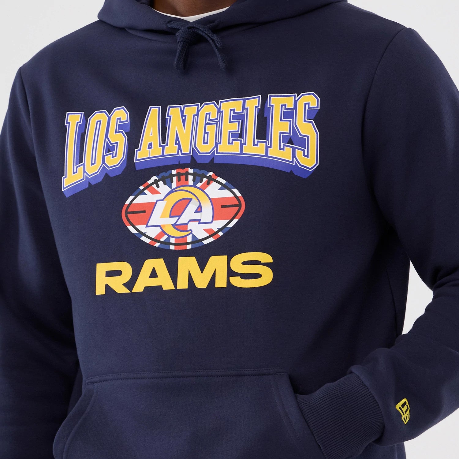 New Era LA Rams NFL International Series Games 2025 Navy Pullover Hoodie, front view showing yellow LOS ANGELES text and a graphic logo on the chest, with a smaller yellow New Era embroidered logo on the left sleeve.