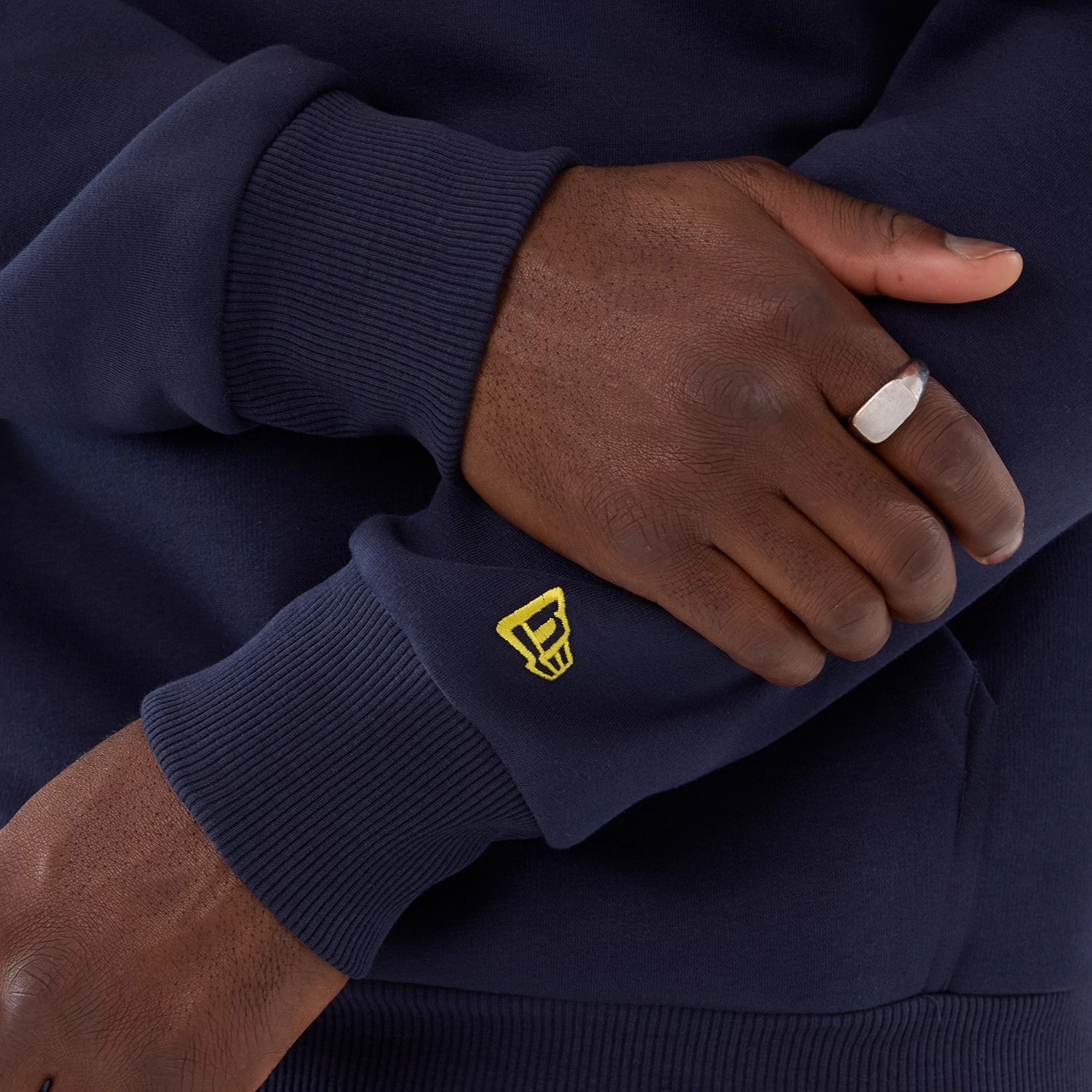 New Era LA Rams NFL International Series Games 2025 Navy Pullover Hoodie, close-up side view showing the ribbed cuffs with a yellow embroidered logo on the sleeve and a glimpse of the navy fabric texture beneath.