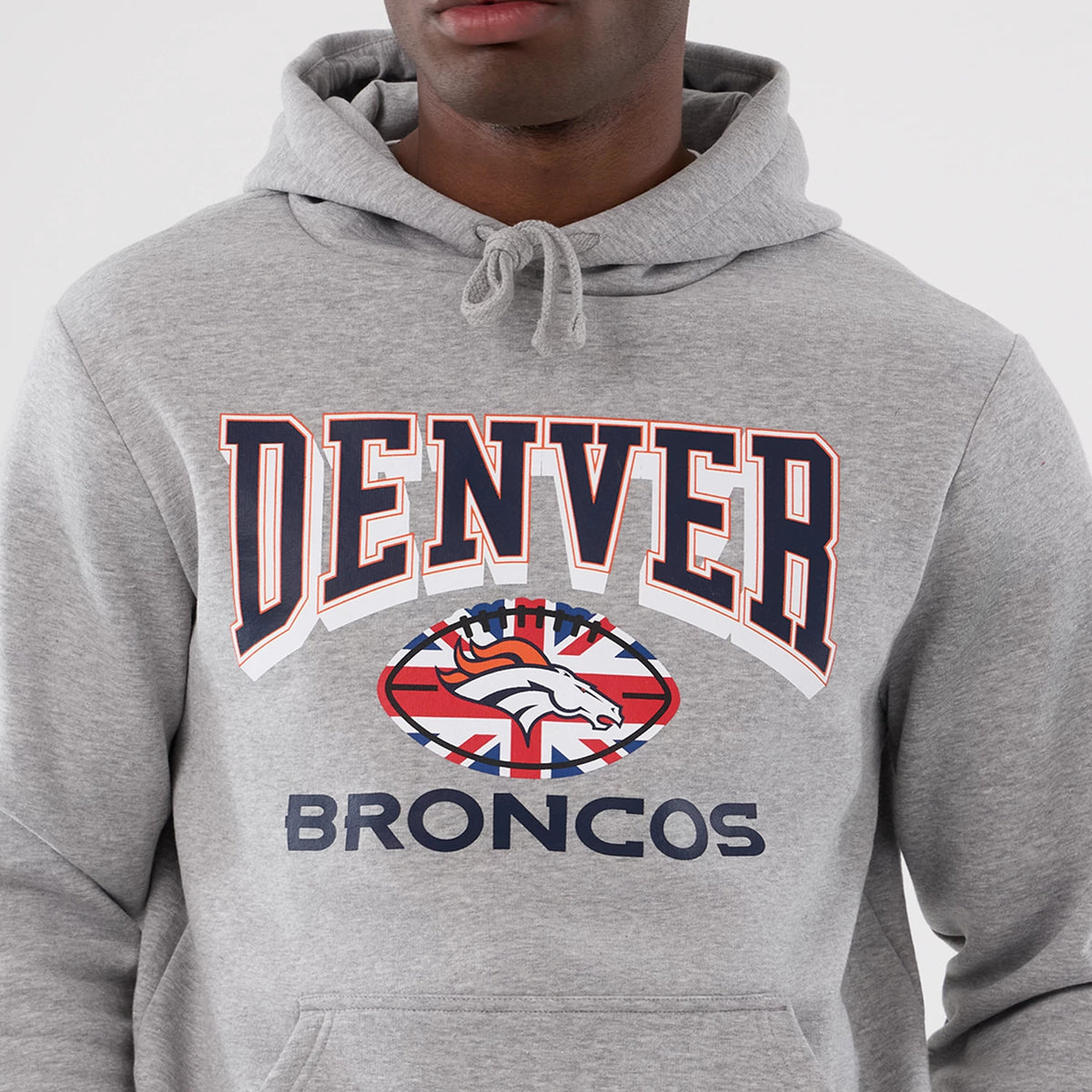 New Era Denver Broncos NFL International Series Games 2025 Grey Pullover Hoodie, front view showing embroidered Denver lettering across the chest, a Denver Broncos logo with a Union Jack flag underneath, and a drawstring hoodie held by a model.