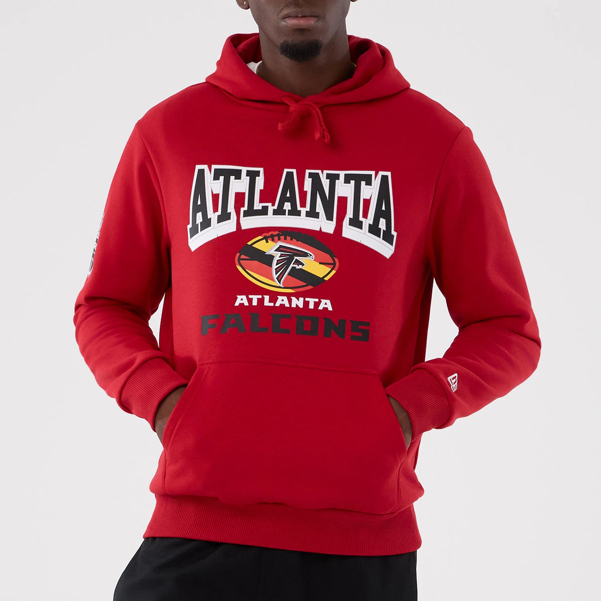 New Era Atlanta Falcons NFL International Series Games 2025 Red Pullover Hoodie, front view on-model showing the ATLANTA lettering above the Falcons logo and below, with a small raised New Era logo on the sleeve cuff.