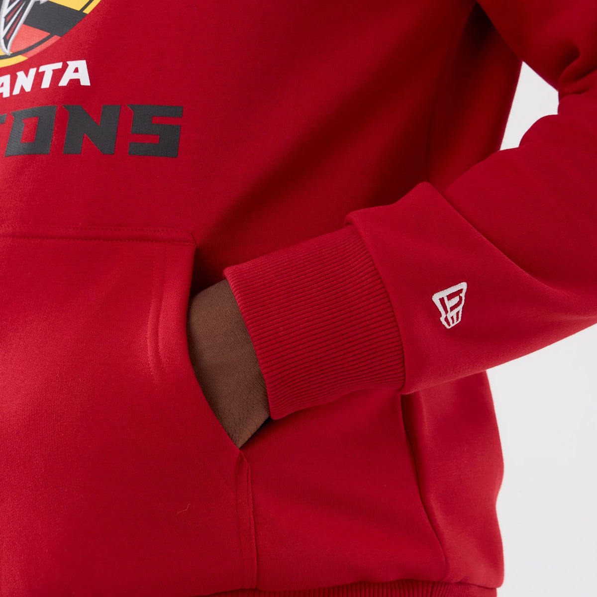 New Era Atlanta Falcons NFL International Series Games 2025 Red Pullover Hoodie, close-up view showing the front pouch with a hand inside, team name printed on the chest, and a small white embroidered logo on the ribbed cuff.