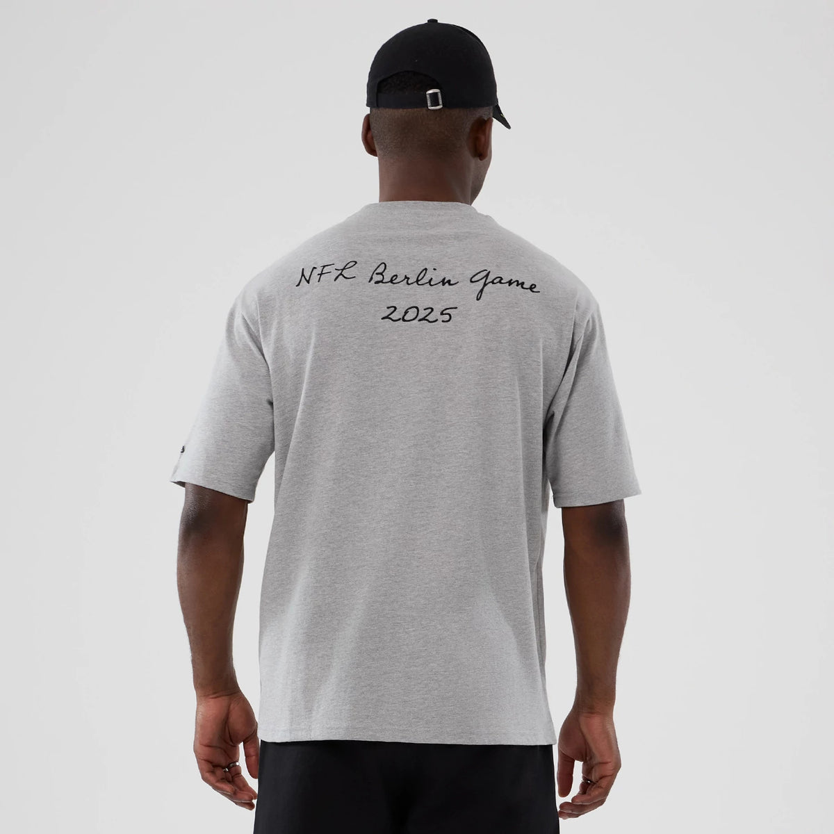 New Era Atlanta Falcons NFL International Series Games 2025 Grey Premium T-Shirt, back view on a model showing NFL Berlin Game 2025 lettering across the upper back in black script style, complementing the plain grey tone of the t-shirt.