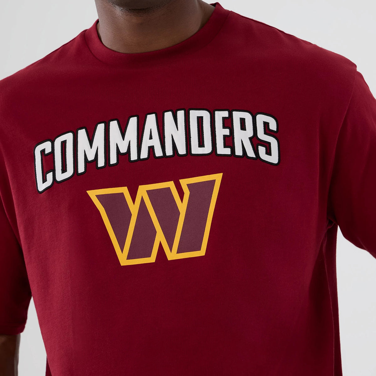 New Era Washington Commanders NFL International Series Games 2025 Dark Red Premium T-Shirt, front view showing Commanders lettering and a large W logo printed on the chest, worn by a model.
