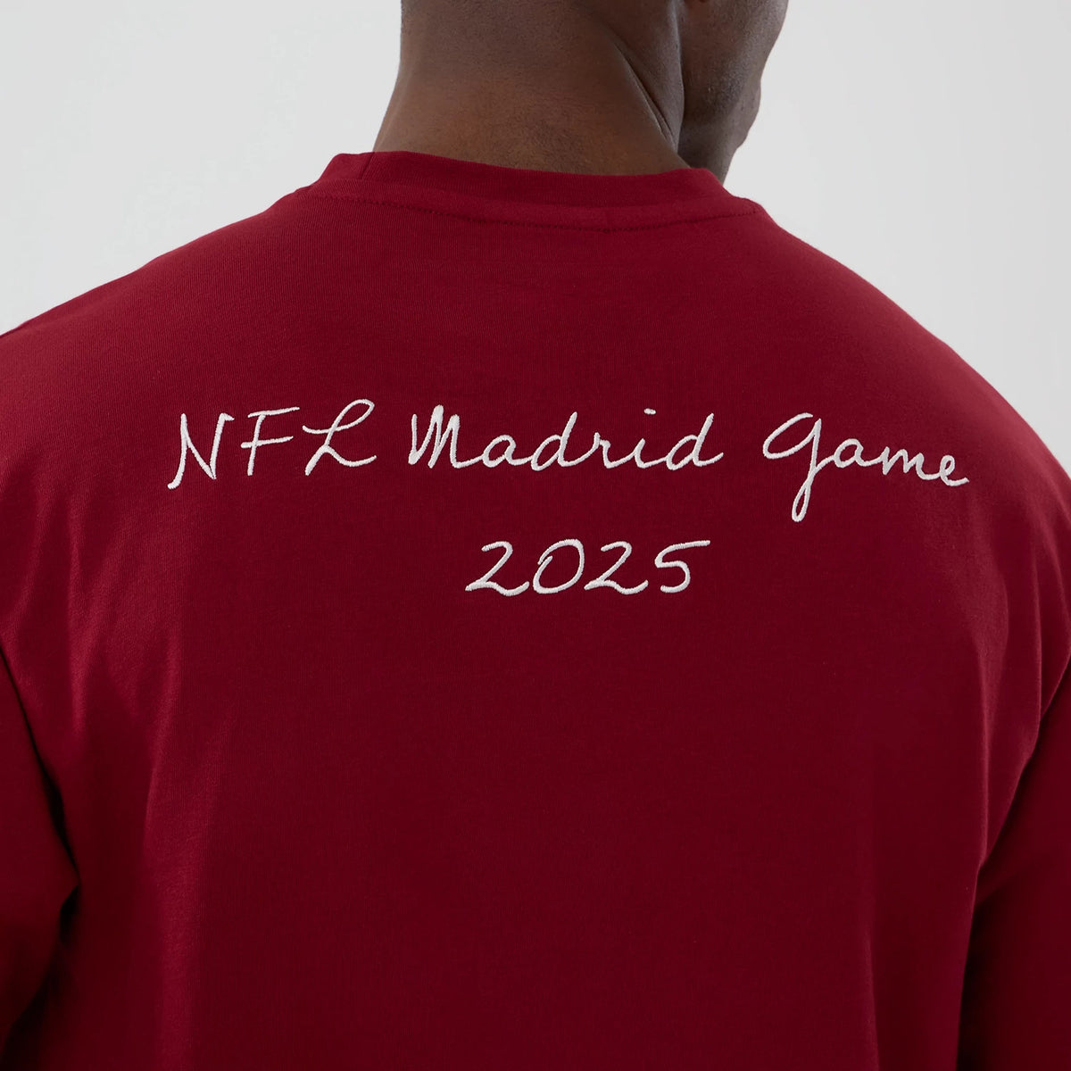 New Era Washington Commanders NFL International Series Games 2025 Dark Red Premium T-Shirt, back view showing on-model white embroidered lettering NFL Madrid Game 2025 across the upper back of the dark red garment.