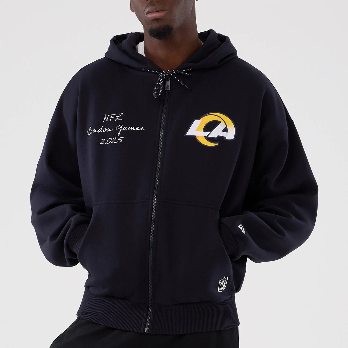 New Era LA Rams NFL International Series Games 2025 Navy Premium Pullover Hoodie, front view showing the large printed LA logo on the chest, a zip closure, NFL London Games 2025 script on one side and a small embroidered New Era logo on the cuff.