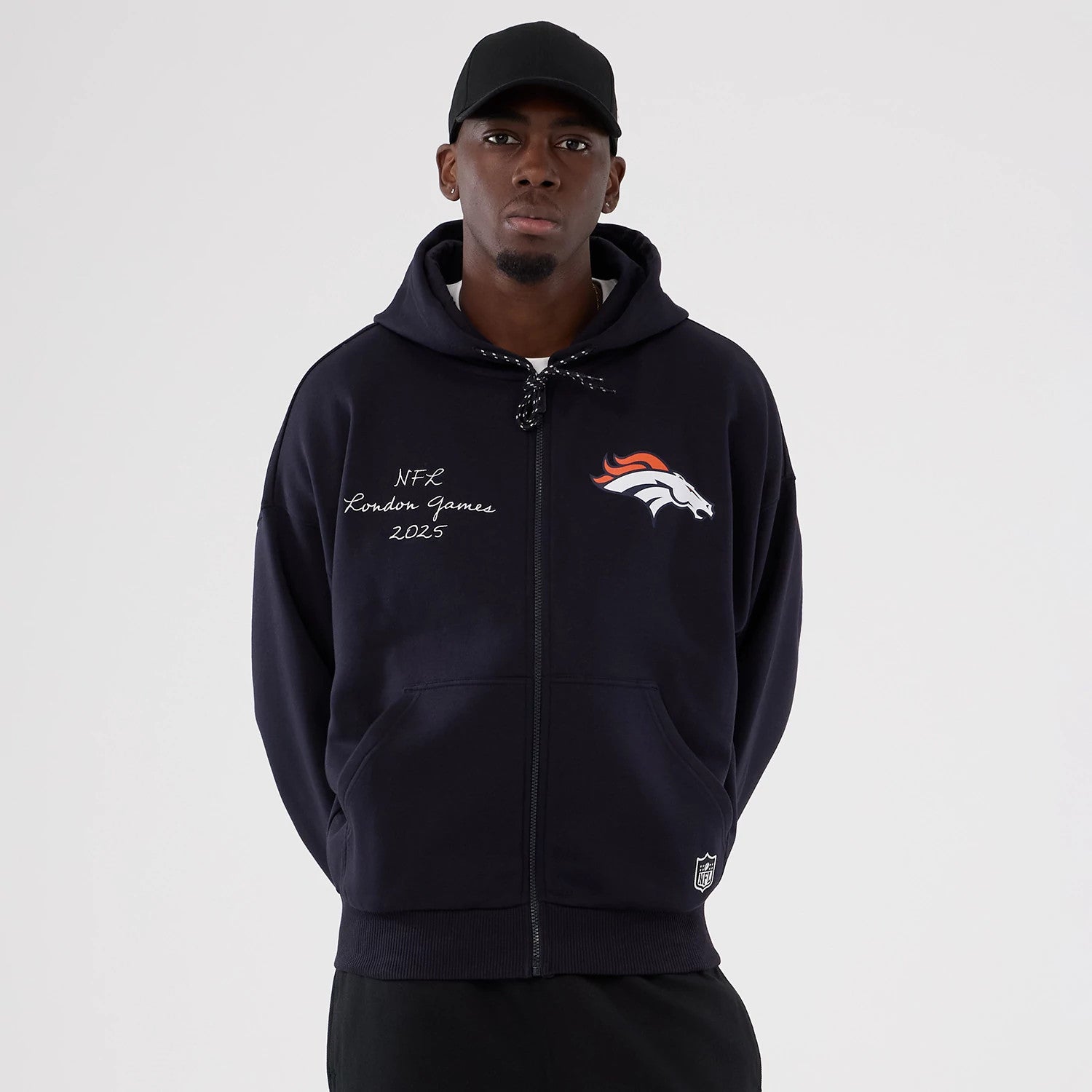 The Male model is wearing Denver Broncos NFL International Series Games 2025 Navy Premium Pullover Hoodie 1
