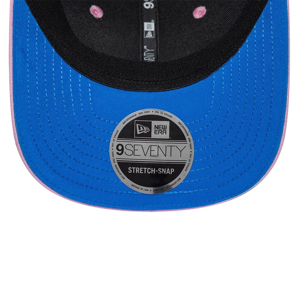 Alpine Racing Franco Colapinto Blue New Era 9SEVENTY Stretch Snap Adjustable Cap, underside view showing the black sweatband, grey 9SEVENTY size sticker on the blue undervisor, and New Era taping with pink interior eyelets.