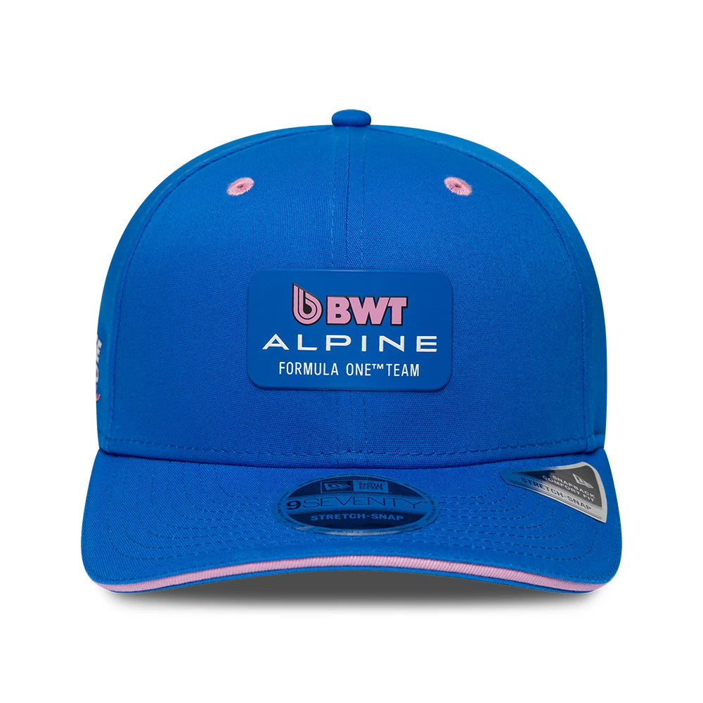 Alpine Racing Team Blue New Era 9SEVENTY Stretch Snap Adjustable Cap, front view showing the BWT Alpine Formula One Team logo patch in pink and white embroidery on the structured blue crown, with a black 9SEVENTY size sticker on the visor.