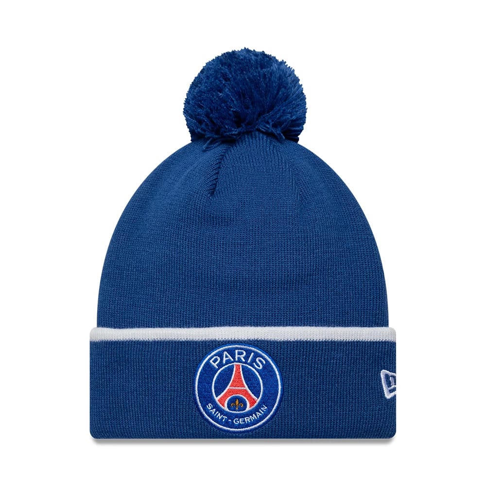 New Era Paris Saint-Germain Core Blue Cuff knit Beanie Hat, front view showing the embroidered PSG club crest centred on the blue fold-over cuff beneath a fluffy blue pom-pom, with the New Era flag logo on the side.