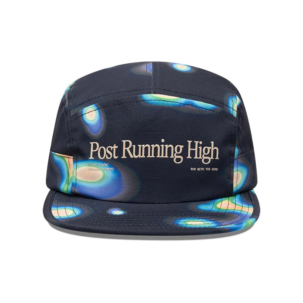 Hermanos Koumori x New Era Navy Camper Cap, front view showing Post Running High text in cream on the structured crown, with abstract blue and green print patterns extending across the dark navy visor and panels.