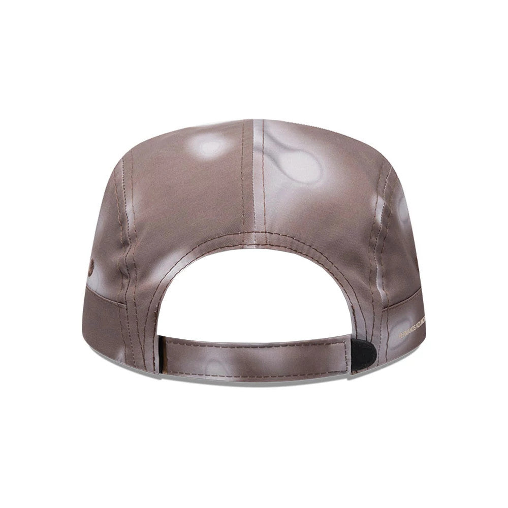 Hermanos Koumori x New Era Dark Brown Camper Cap, rear view showing the adjustable strap with a velcro closure and abstract light pattern on the dark brown panels, featuring branding near the strap.